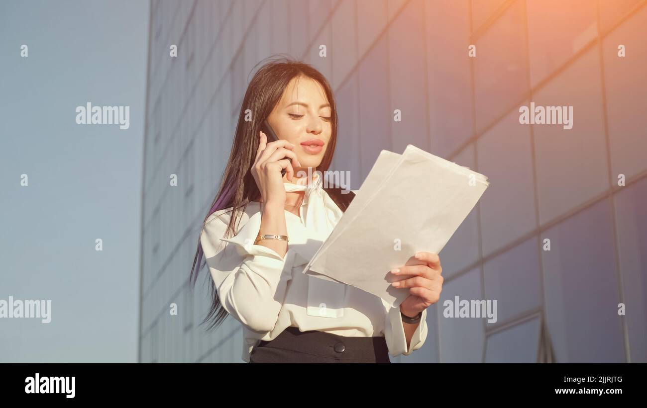 Manager walks talking on phone and looking at documents Stock Photo