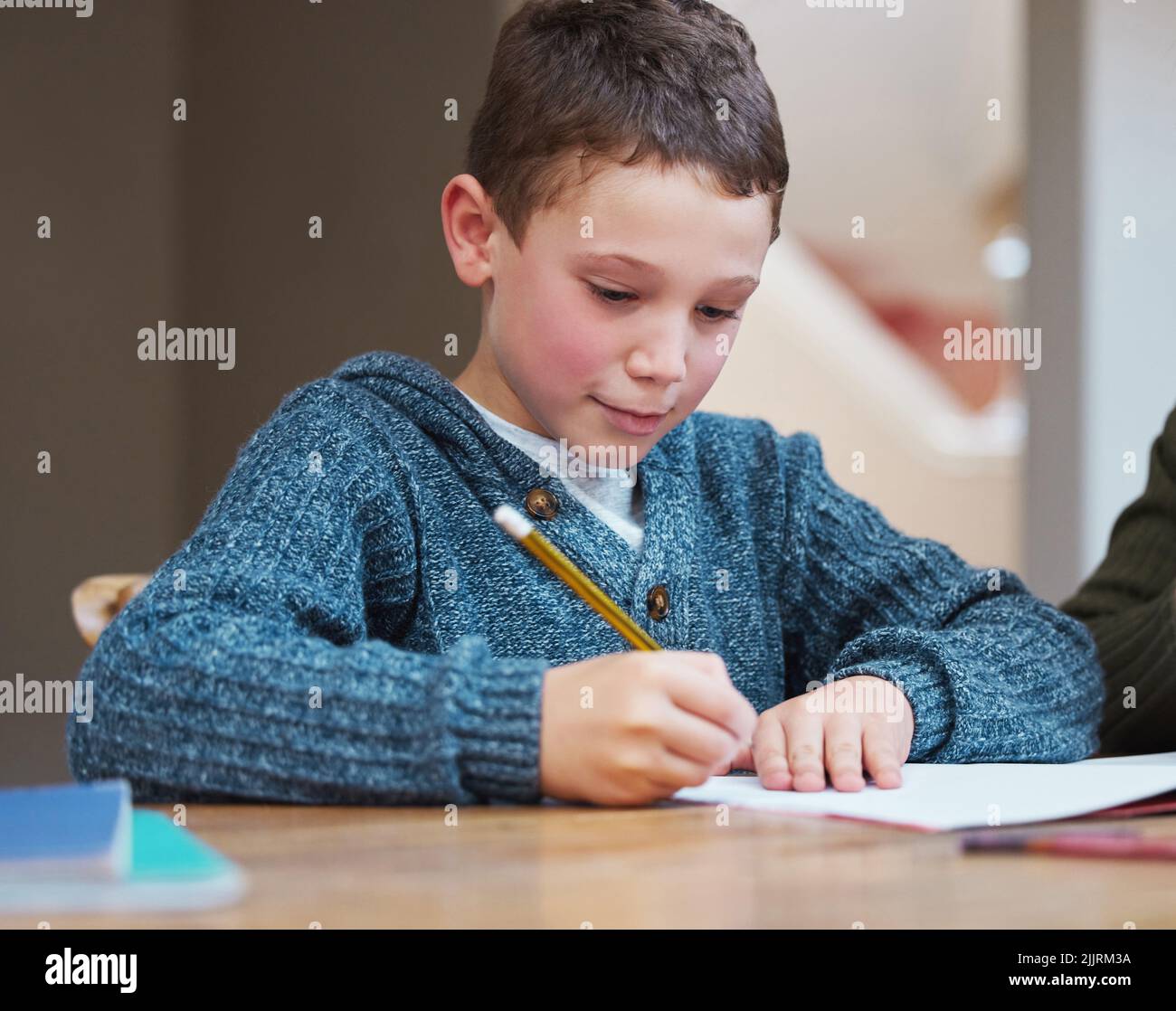 I miss seeing my school friends. a young boy completing his homework. Stock Photo