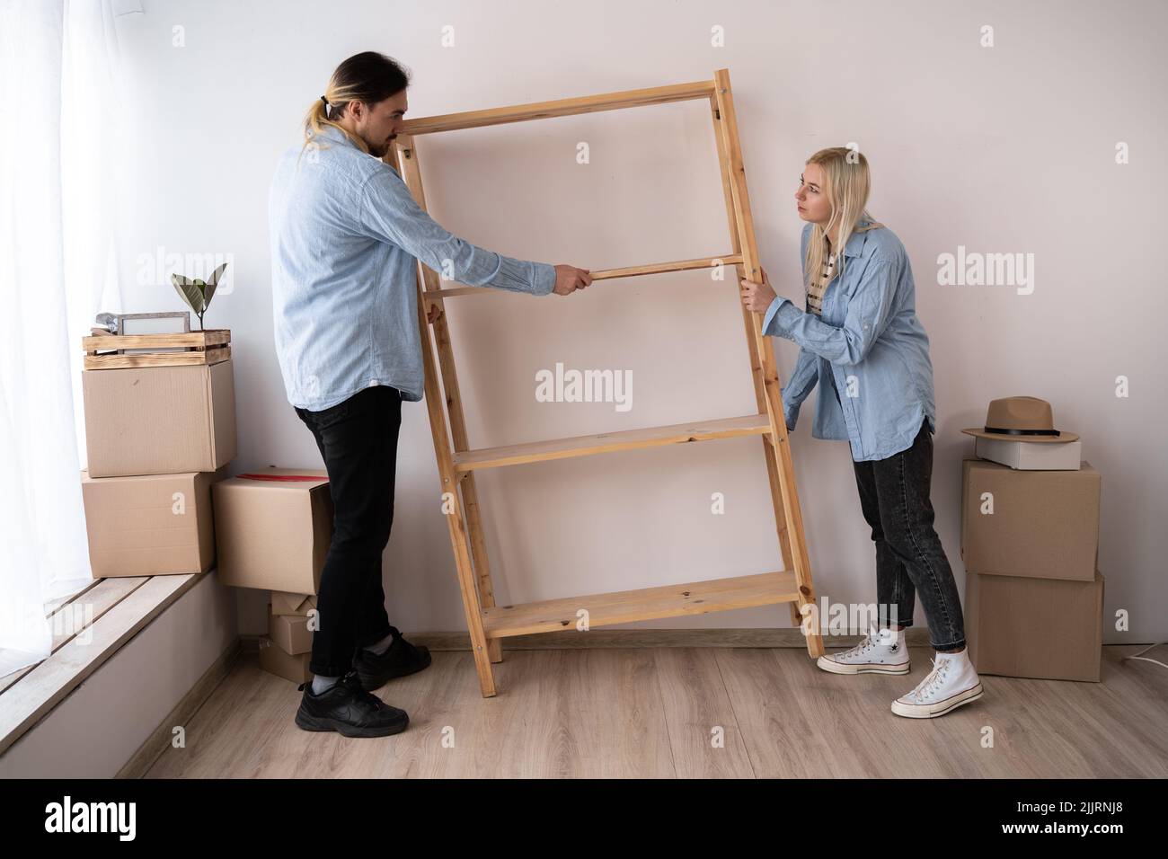 Happy couple moving into new home and putting the shelf. carry new