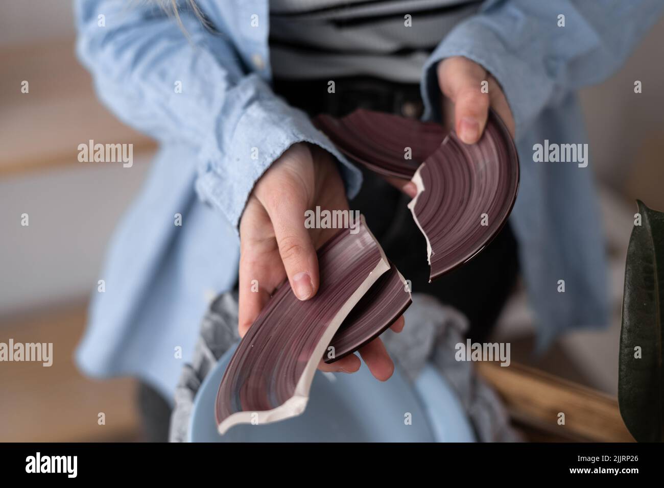 Close up of female hand with a broken dish. Woman received an Internet order parcel with tableware. Moving into a new house. Unpacking Stock Photo