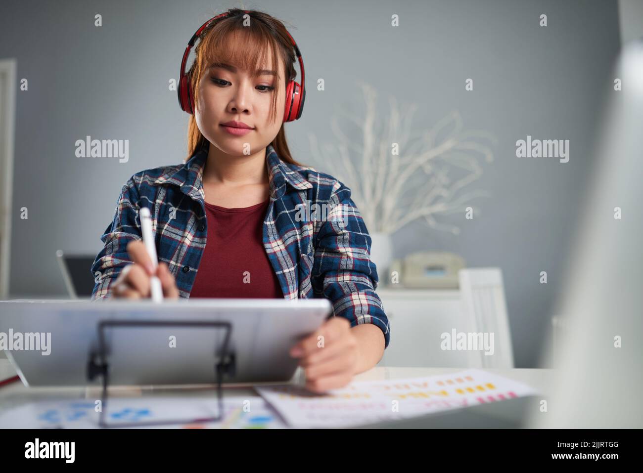 Concentrated young photo editor listening to music in headphones while