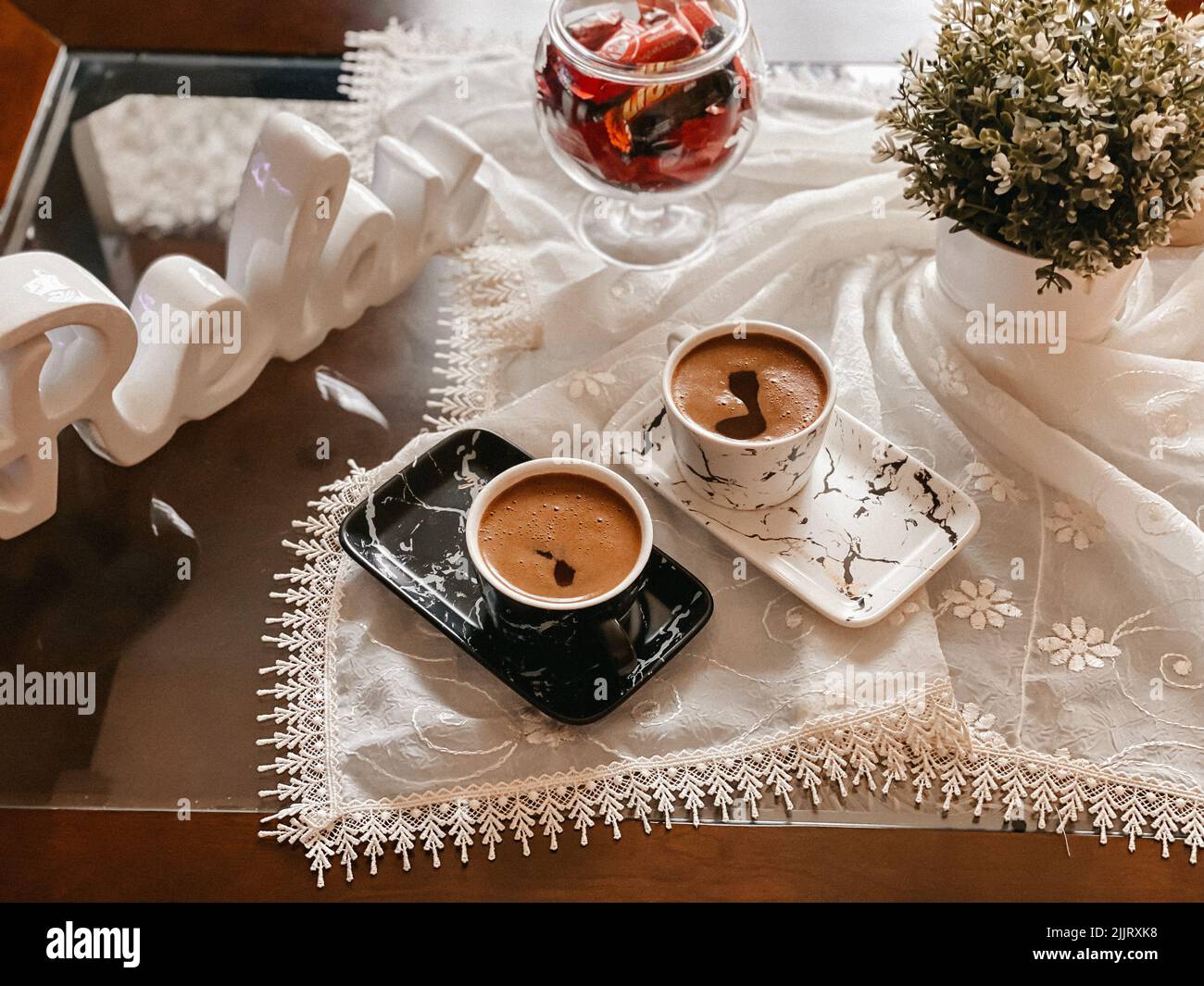 A top view of beautifully arranged cups of coffee on a tablecloth decorated with flowers Stock Photo
