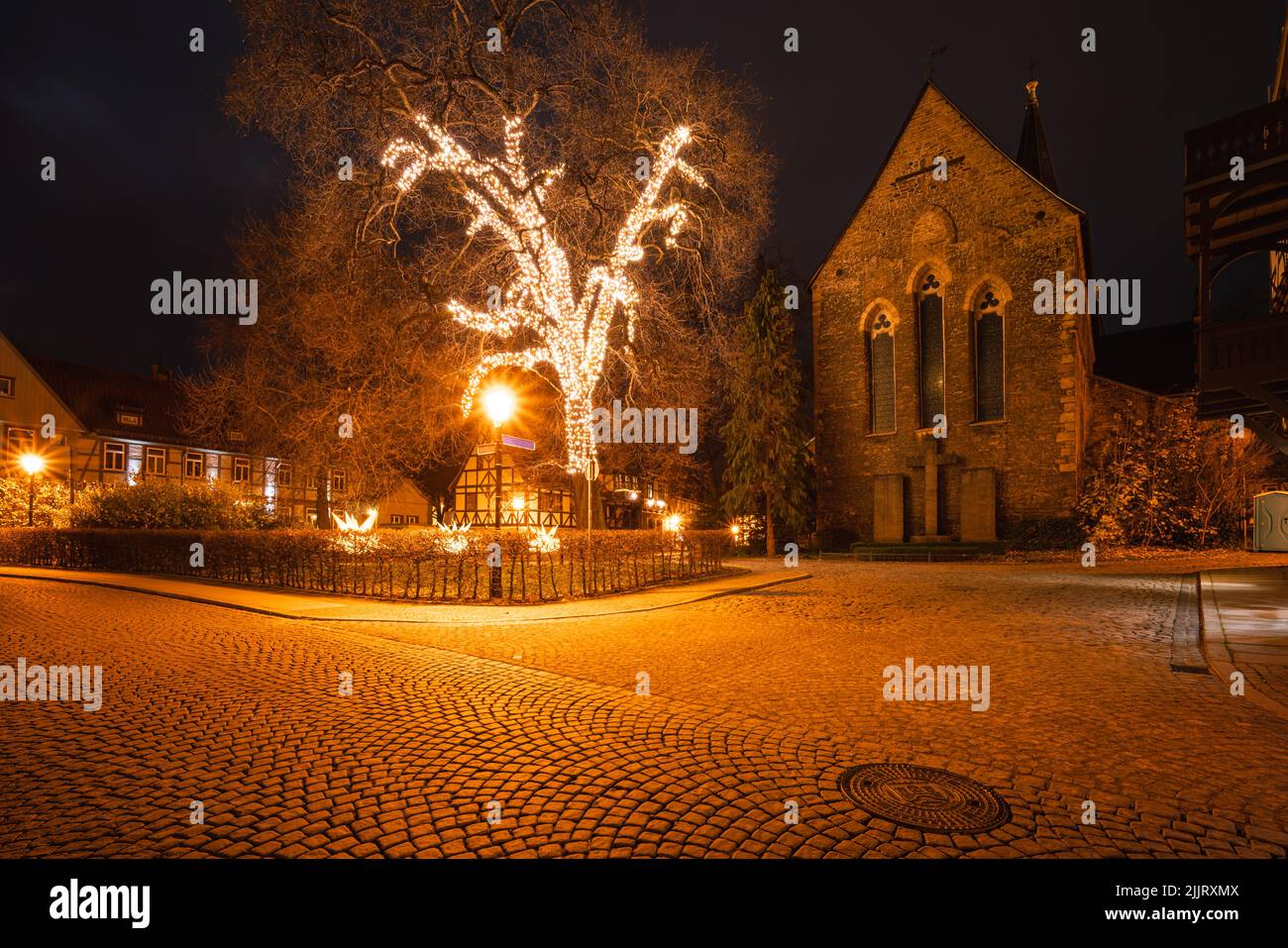 Large tree illuminated with Christmas lights in front of a church in Wernigerode Stock Photo