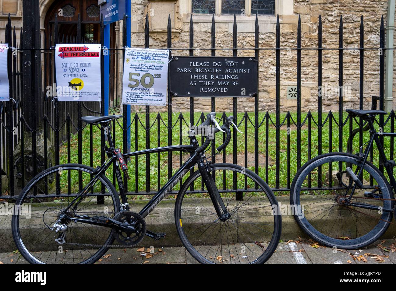 amusing sign being ignored by cyclists. cycle bicycle bike bikes cycles bicycles chained to fence fencing Oxford England Stock Photo