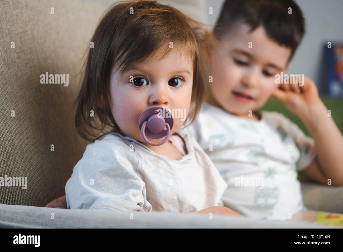 A portrait of two kids sitting on the sofa at home. Family care. Happy