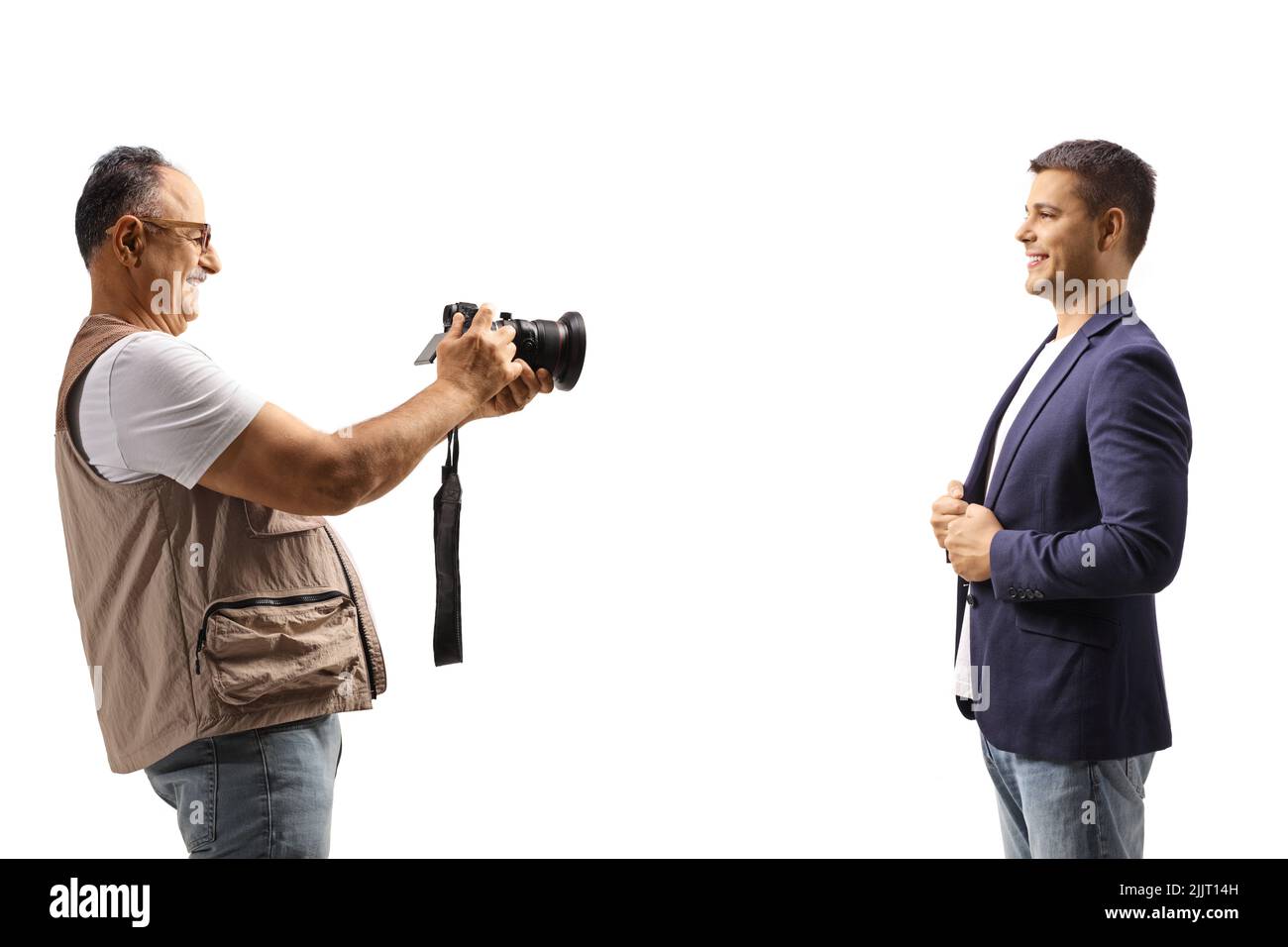 Mature man taking a photo of a young man with a professional camera isolated on white background Stock Photo