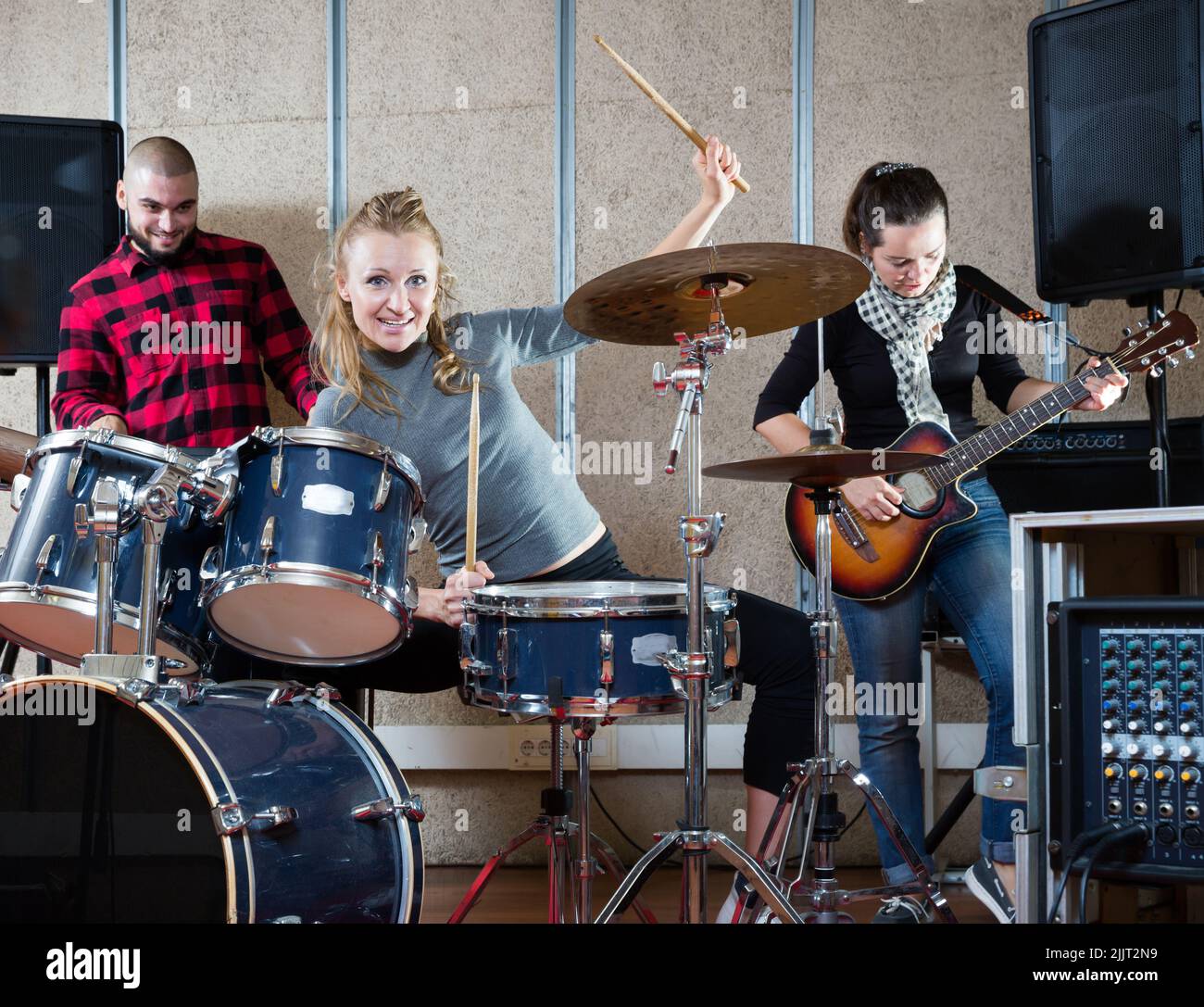 Music band with smiling girl drummer rehearsing Stock Photo