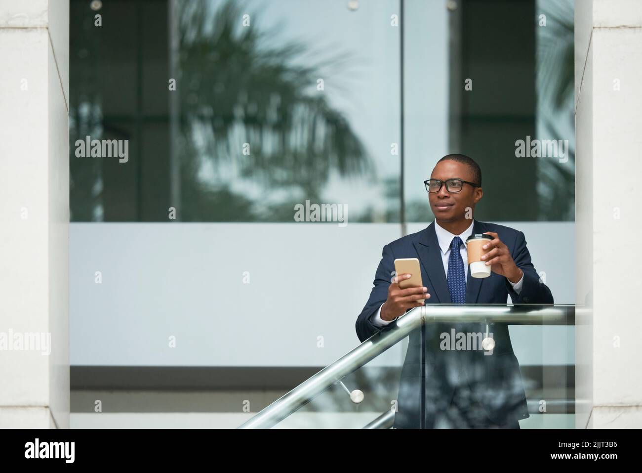 Pensive young business executive with coffee and smartphone Stock Photo