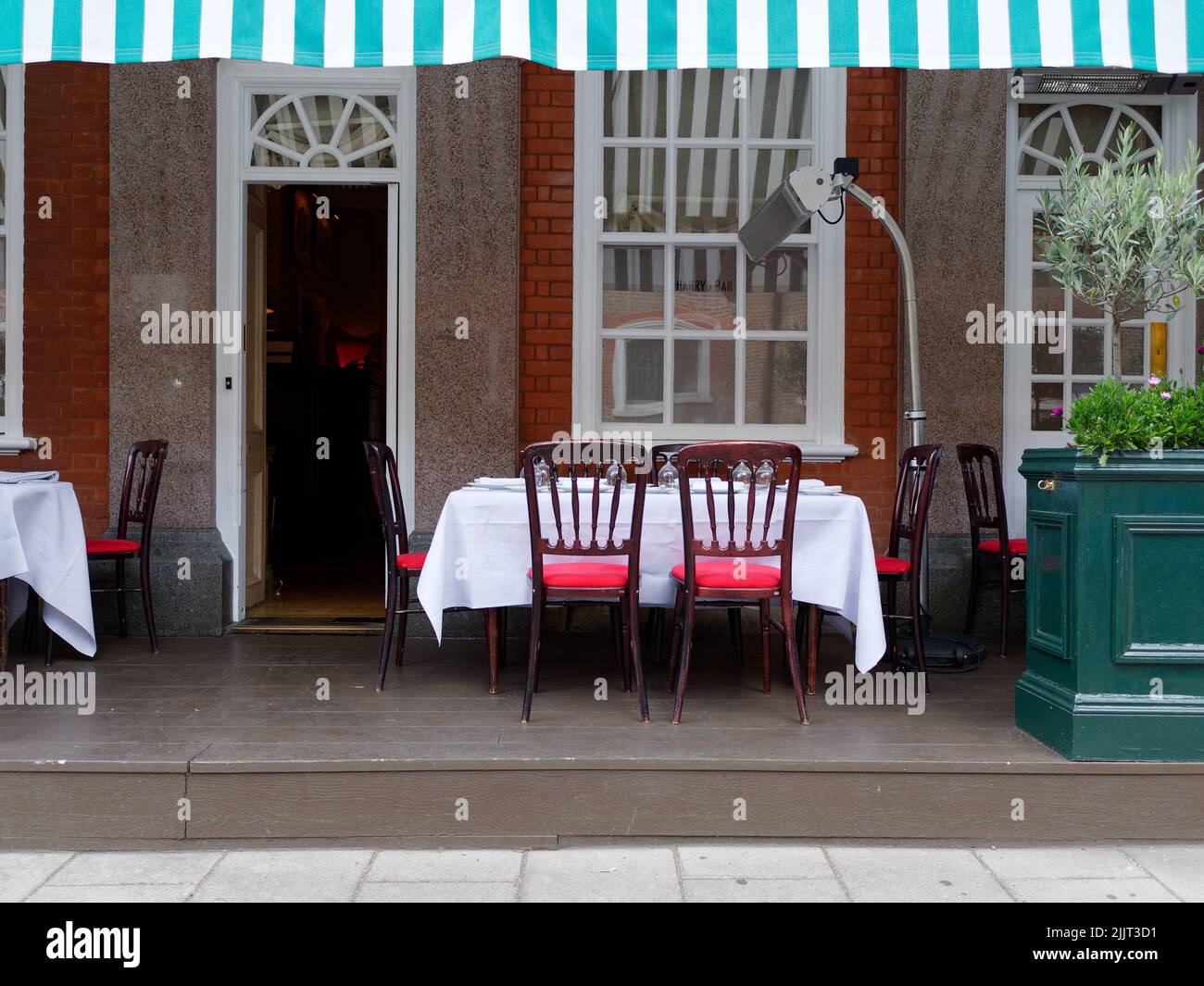 London, Greater London, England, June 30 2022: Table and chairs and heater outside a chic private club with canopy in the Park Lane area Stock Photo