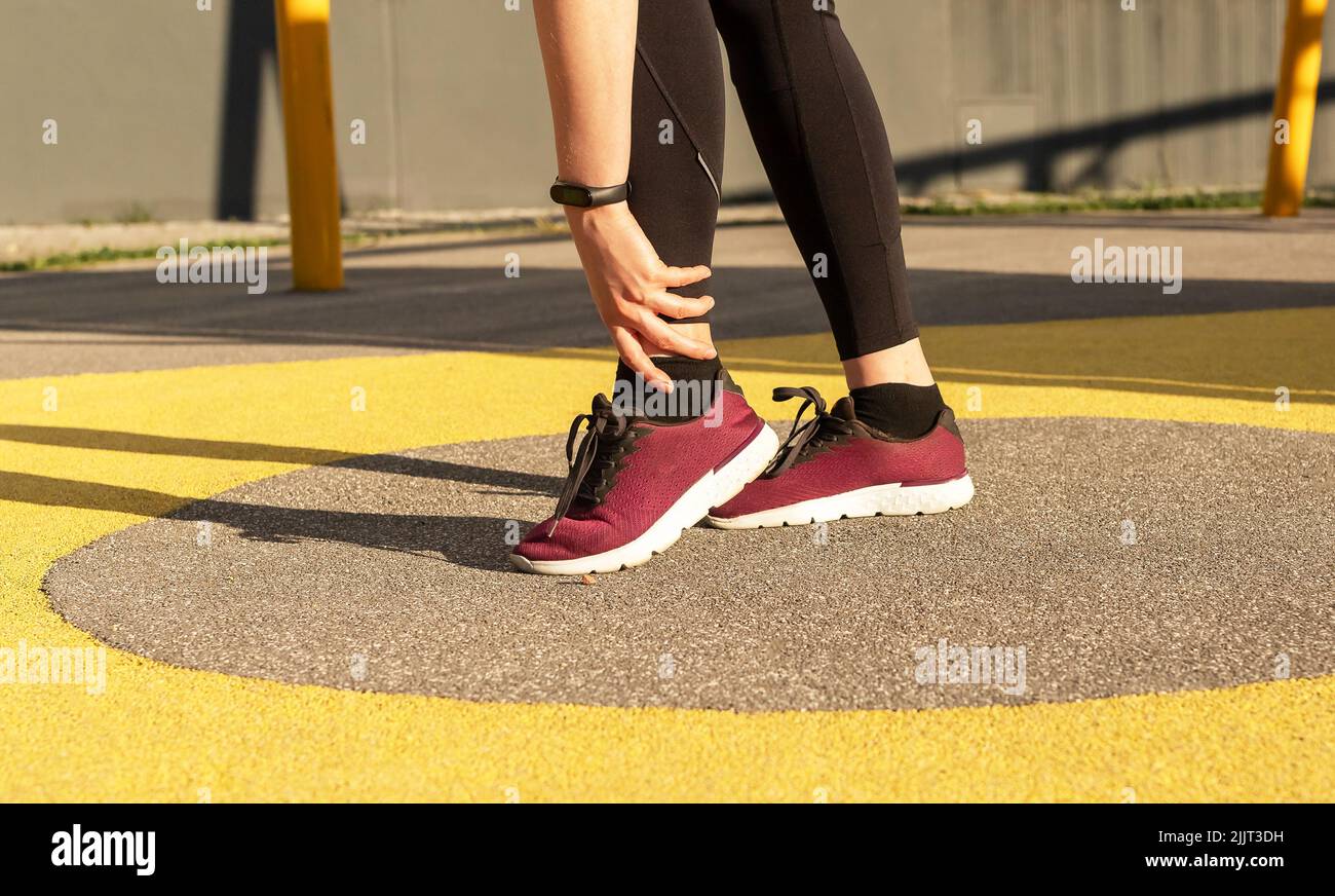 Athlete ankle pain, sports injury. Woman holding painful foot. Sprains, strains, fracture