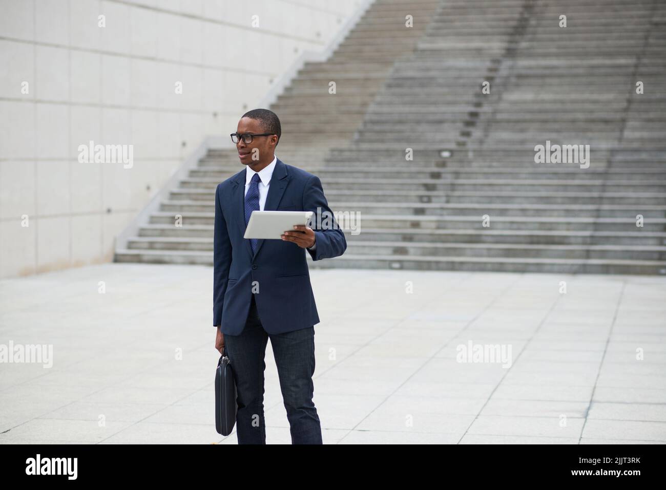 Young businessman with digital tablet standing outdoors Stock Photo