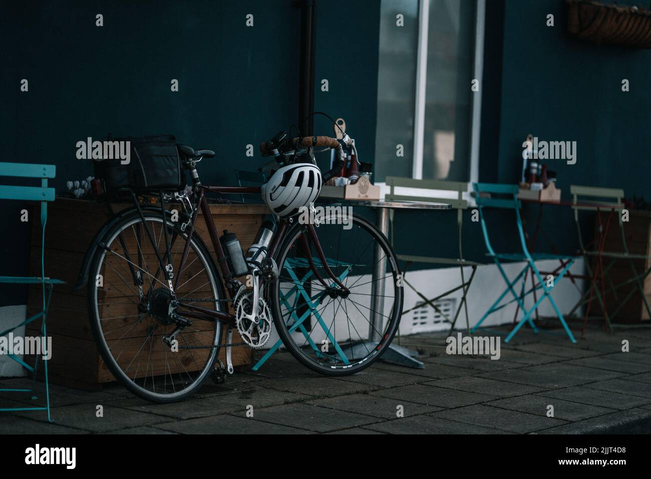 A bicycle with a helmet is standing near an empty counter and chairs Stock Photo