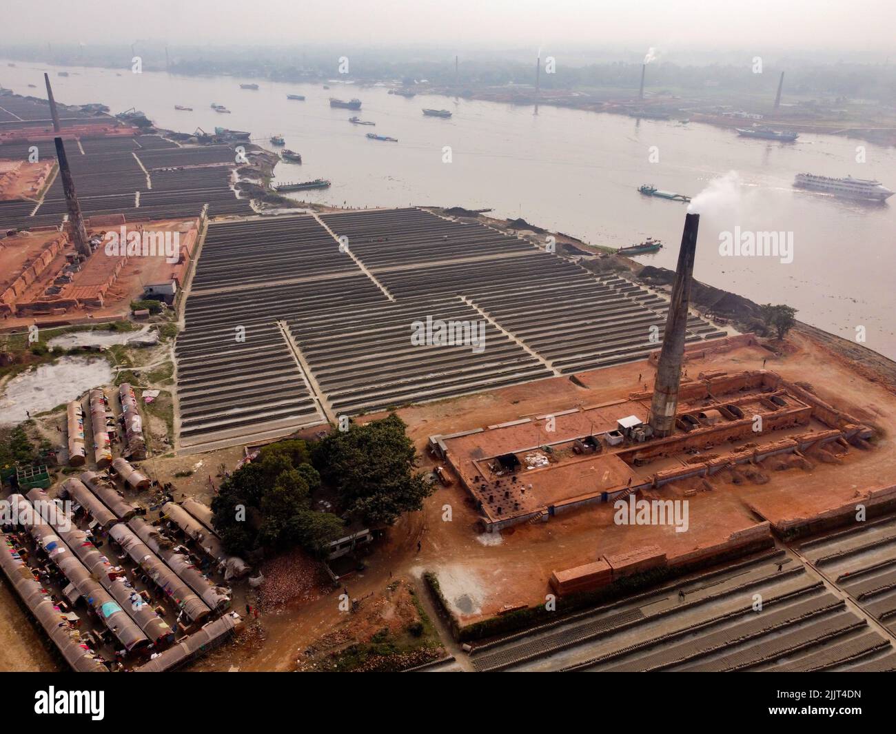 Dhaka, Dhaka, Bangladesh. 28th July, 2022. Aerial view of smoke pouring from the chimney stack of brick kilns in Dhaka, Bangladesh. Brick kilns are responsible for 17% of the country's annual carbon dioxide (CO2) emission and 58% of Dhaka city's air pollution. There are approximately 5000 privately operated brick kilns within Bangladesh, including 1000 around the capital, Dhaka. With its 160 million inhabitants, Bangladesh is a country in constant demand for bricks as the primary material for construction of buildings in the era of urbanization. Brick Kilns release over 1,072 million tonnes o Stock Photo