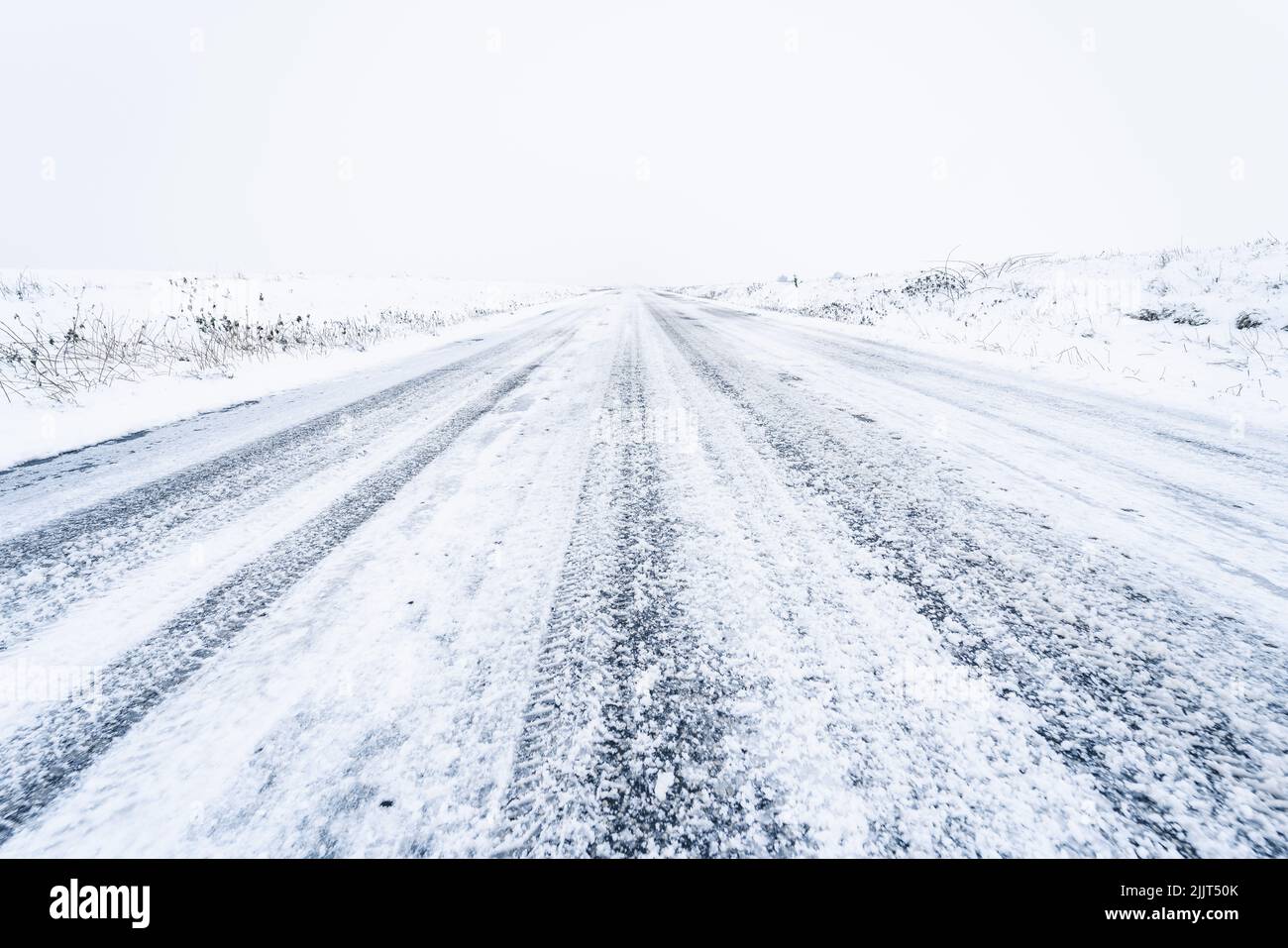 A vanishing point shot of a snowy countryside road Stock Photo