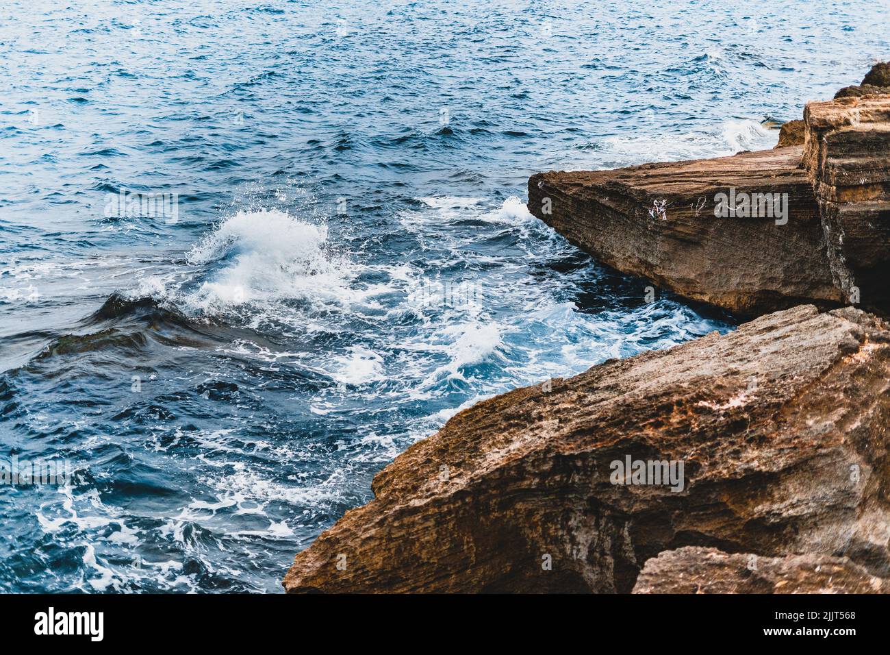 An ocean waves hitting enormous rocks on the shore - perfect for the background Stock Photo