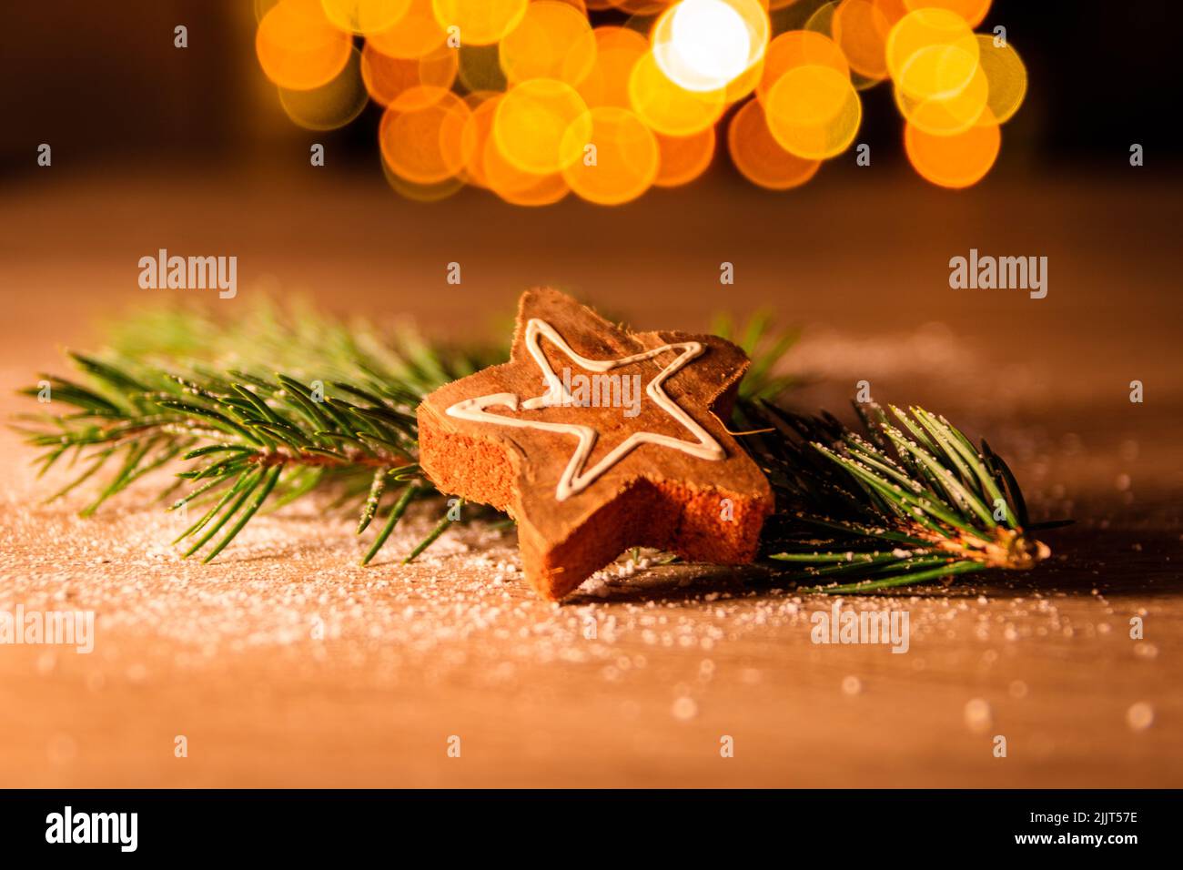 A star-shaped cookie on pine leaves against bokeh background Stock Photo