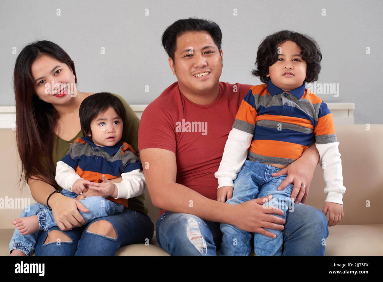Happy Filipino family of four sitting on sofa Stock Photo