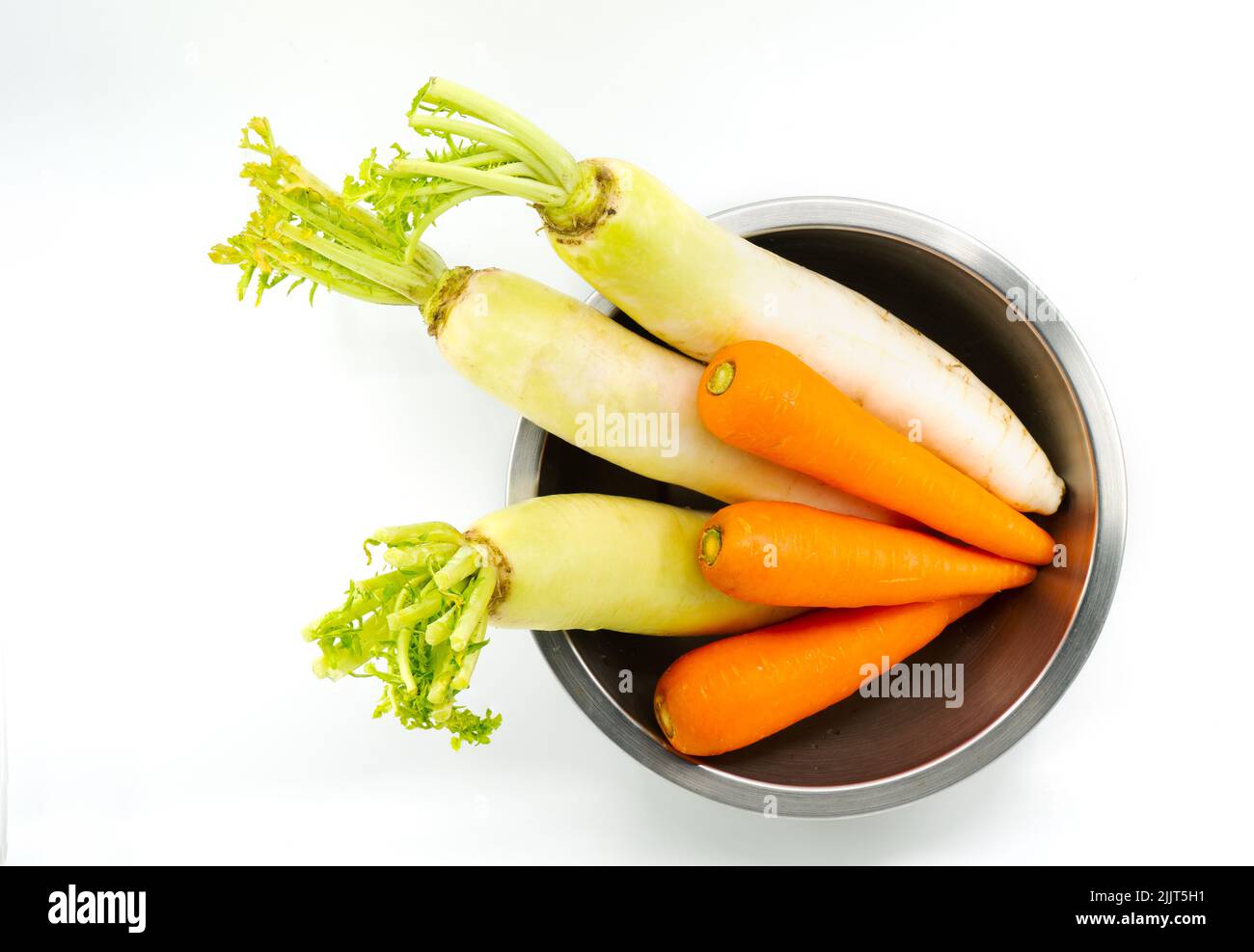Organic carrots and white radishes in round shape stainless steel bowl, unpeeled carrots and radishes, top view image, isolated image on white backgro Stock Photo