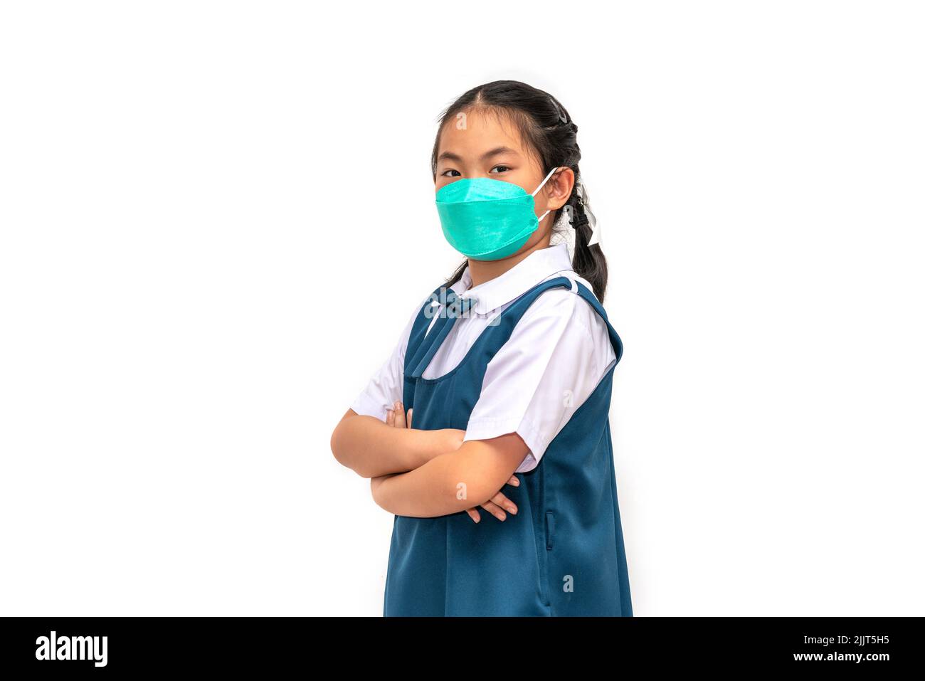 Asian student small child girl wears face mask or medical face mask, student in uniform, arms cross on chest, eyes look at camera with confident emoti Stock Photo