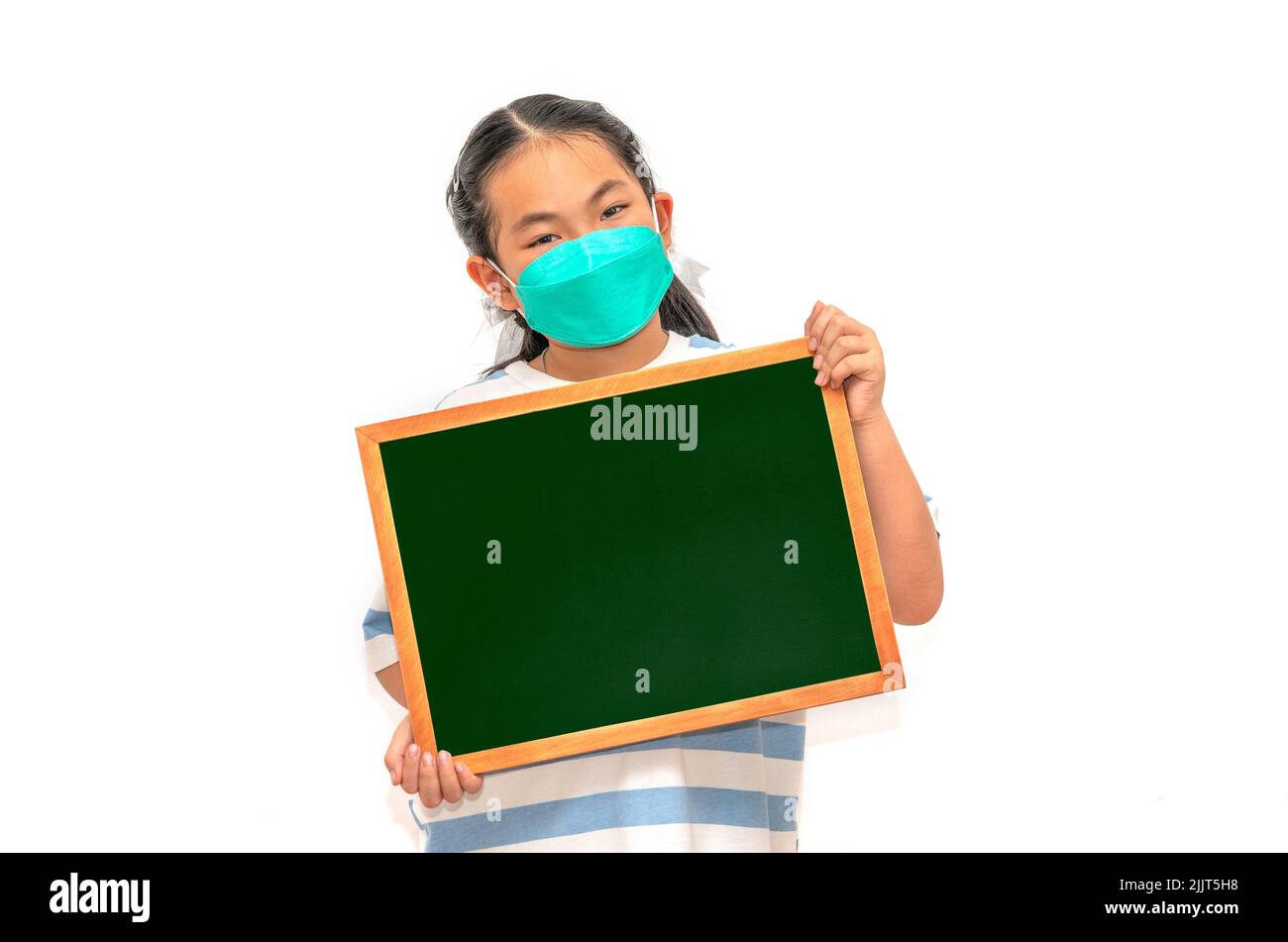 Portrait Asian student child in casual, holding small blackboard or chalkboard, wearing face mask, isolated image on white background, concept for bac Stock Photo