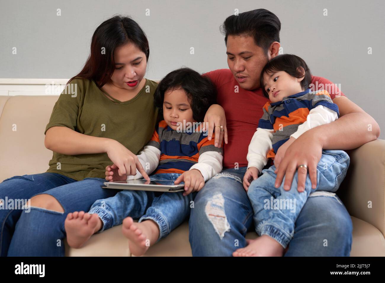 Filipino family gathered together to use an app on digital tablet Stock Photo