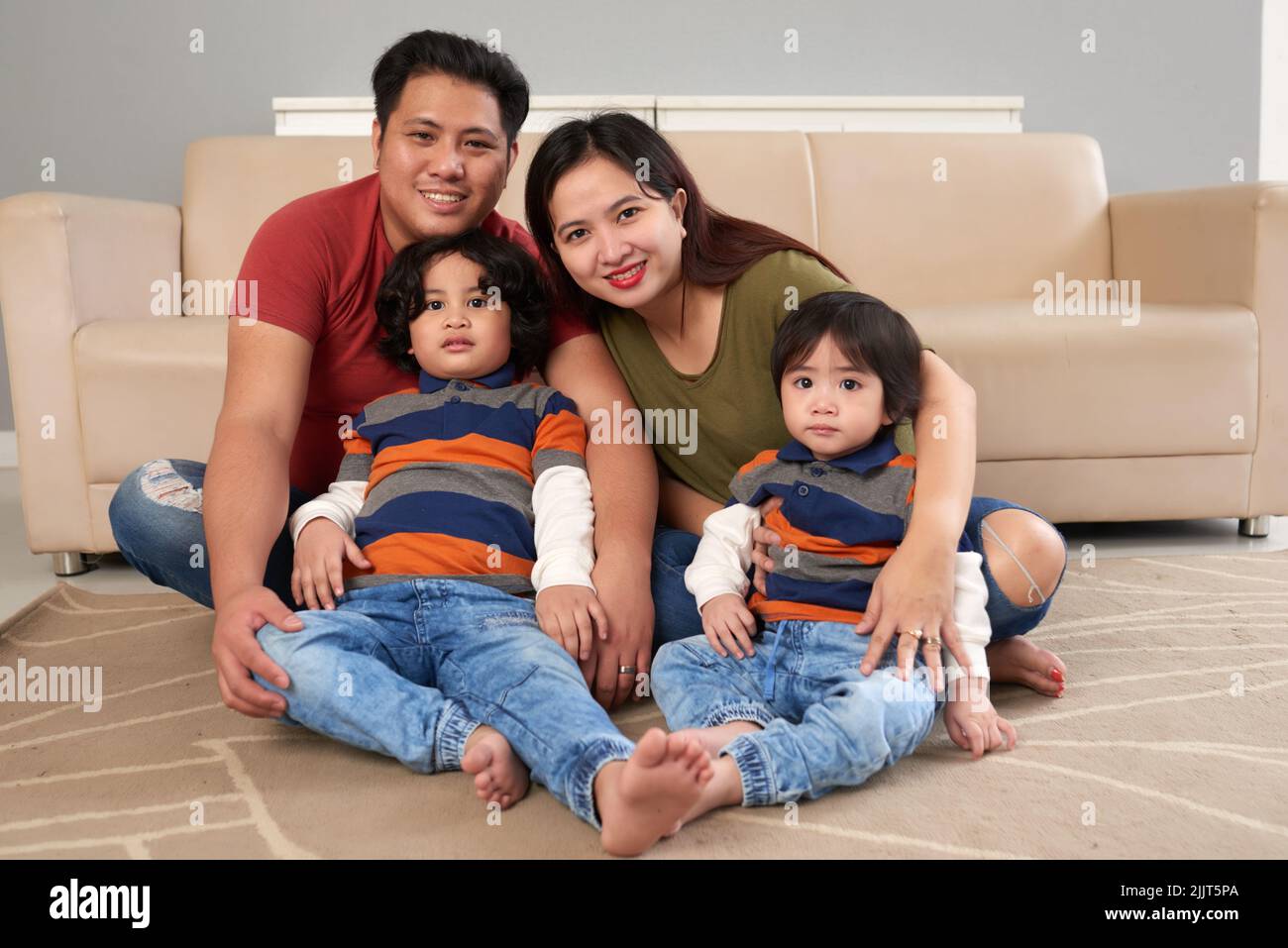 Cheerful Filipino family sitting on the floor in living room Stock Photo
