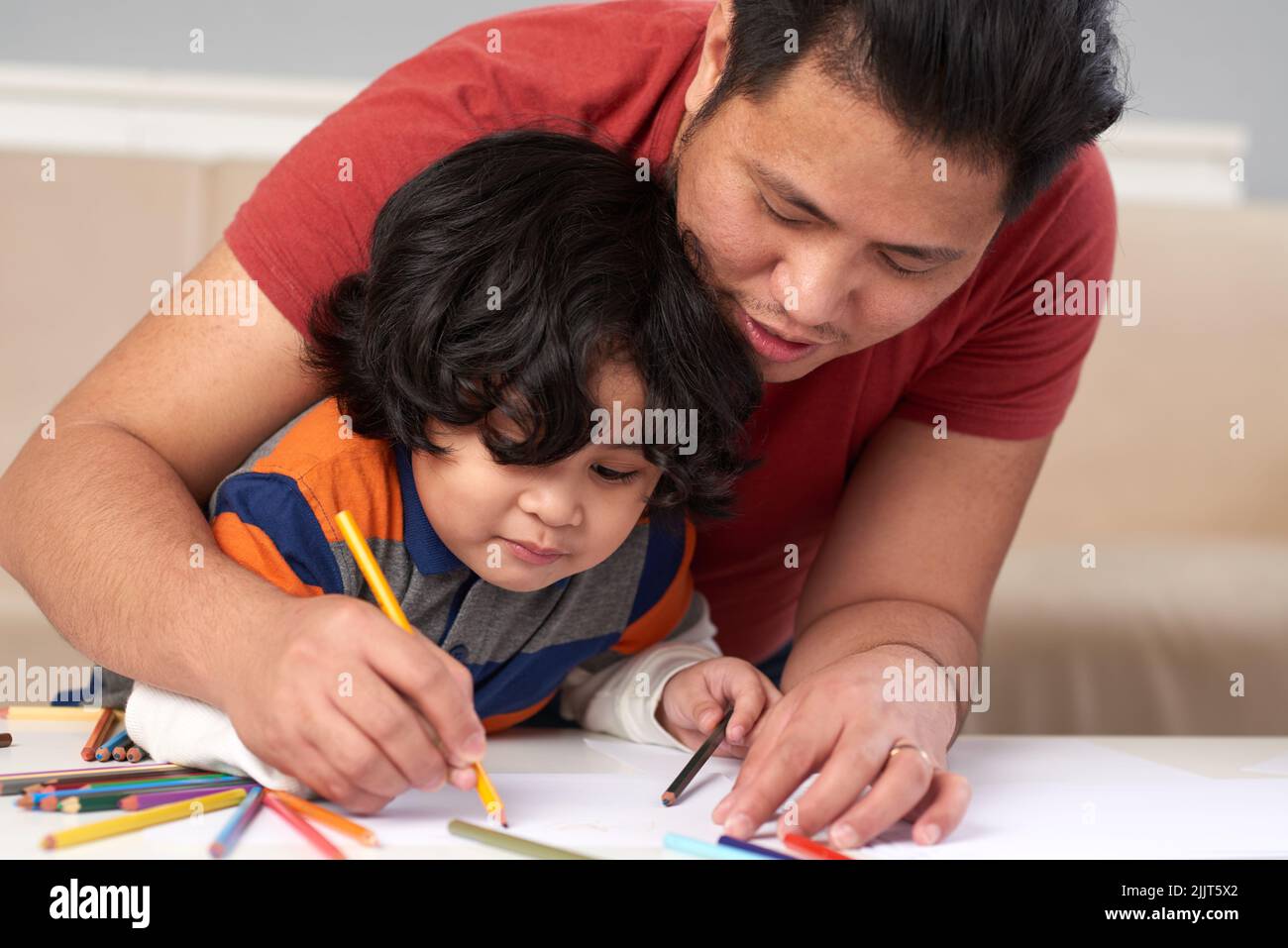 Filipino father and son drawing together with pencils Stock Photo