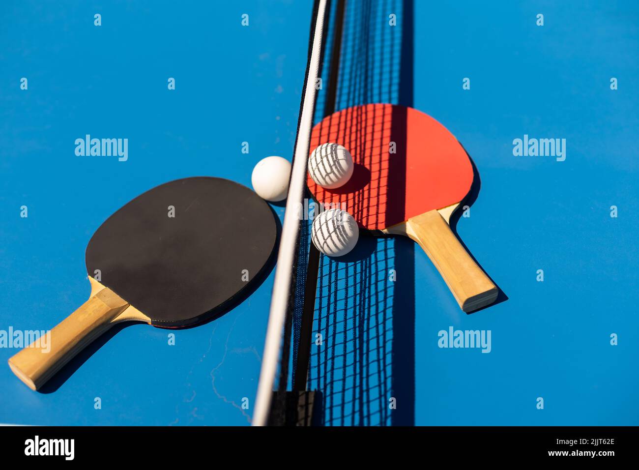 Table tennis rackets and a white plastic ball on a blue background ...