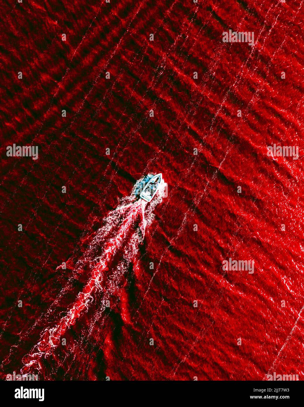 An aerial top view of a boat sailing in a sea with red water Stock ...