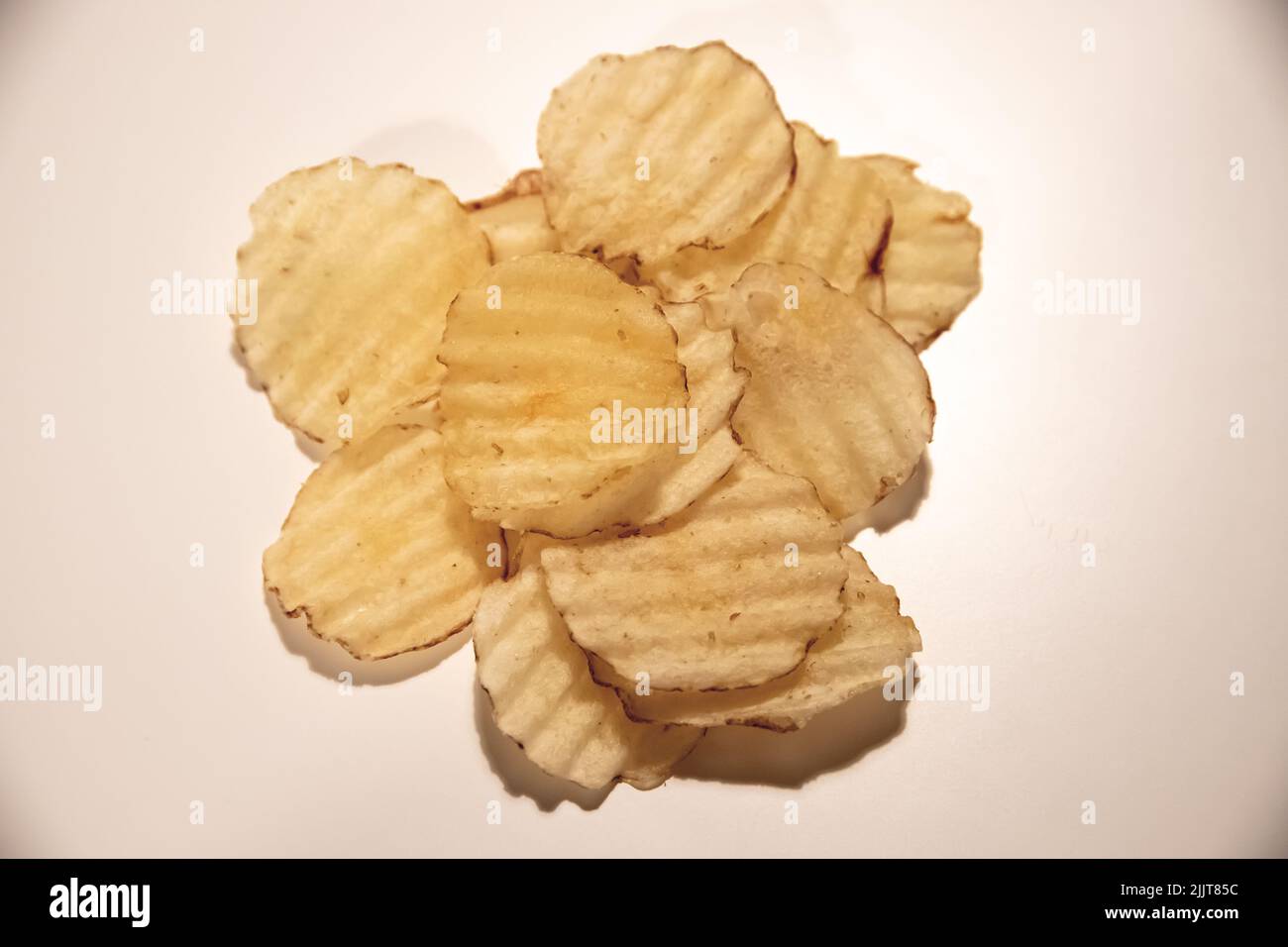 A heap of fried potato chips isolated on a pink background Stock Photo