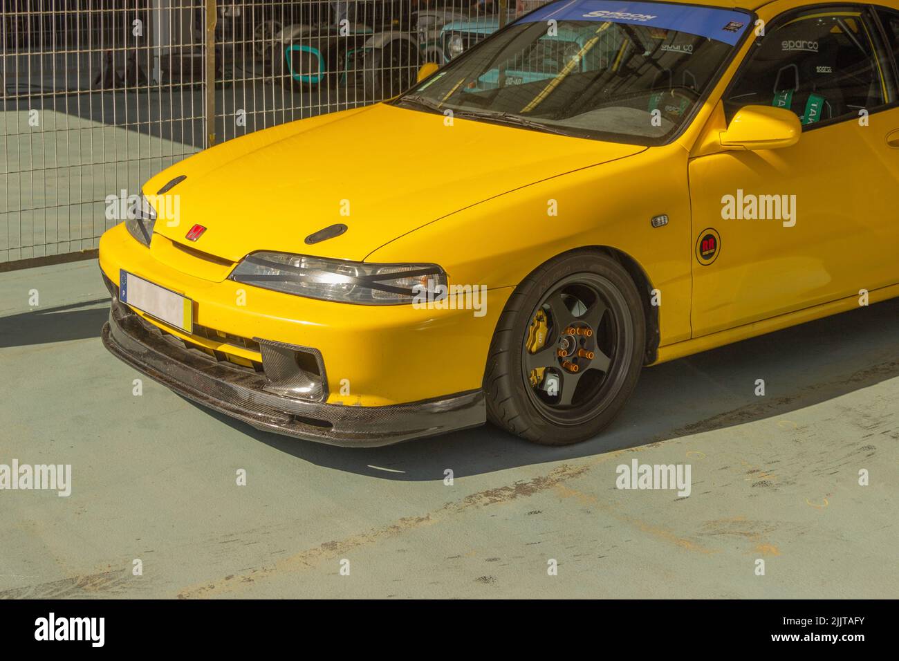 A vibrant yellow Honda Integra Type R sportscar parked outside under bright sunlight Stock Photo