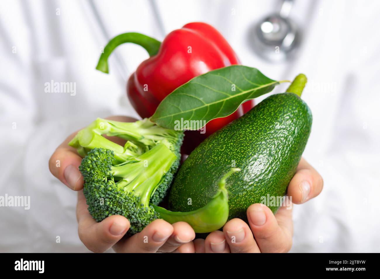 Healthy food Nutritionist doctor holds fresh broccoli avocado and peppers in his hands Stock Photo