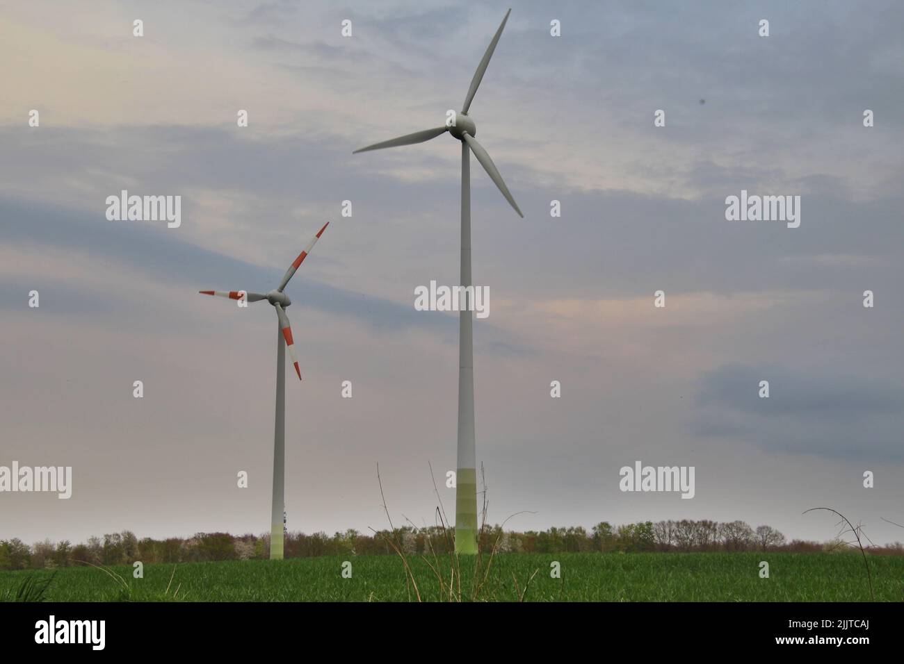 Two modern wind turbines in a field at sunset during summer Stock Photo ...