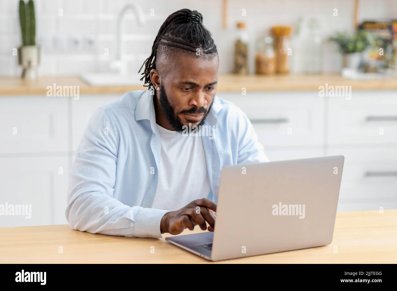 Portrait of focused African American freelancer working remotely online at home using computer Stock Photo