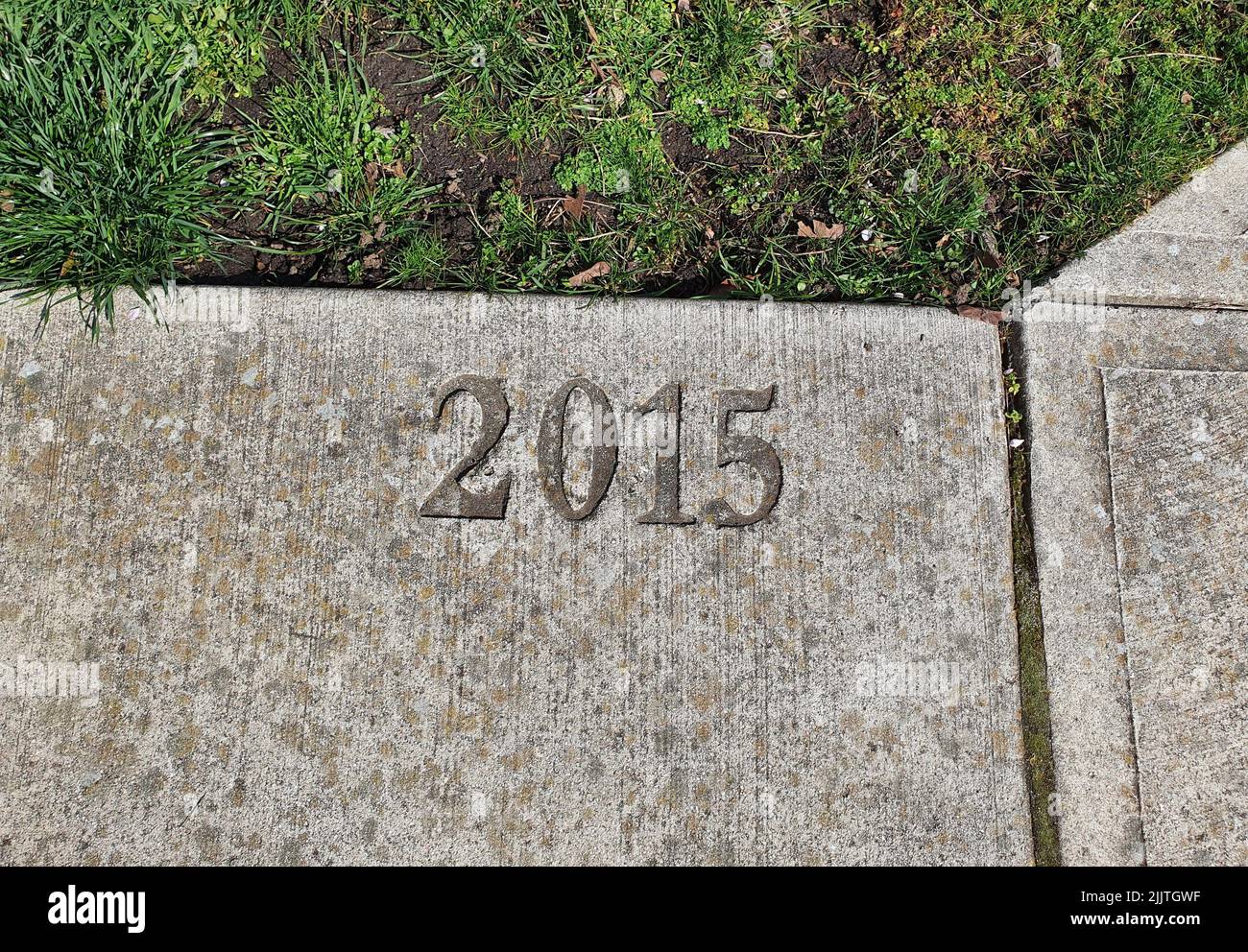 A top view of gray color paving slab surrounded by grass with 2015 numbers Stock Photo