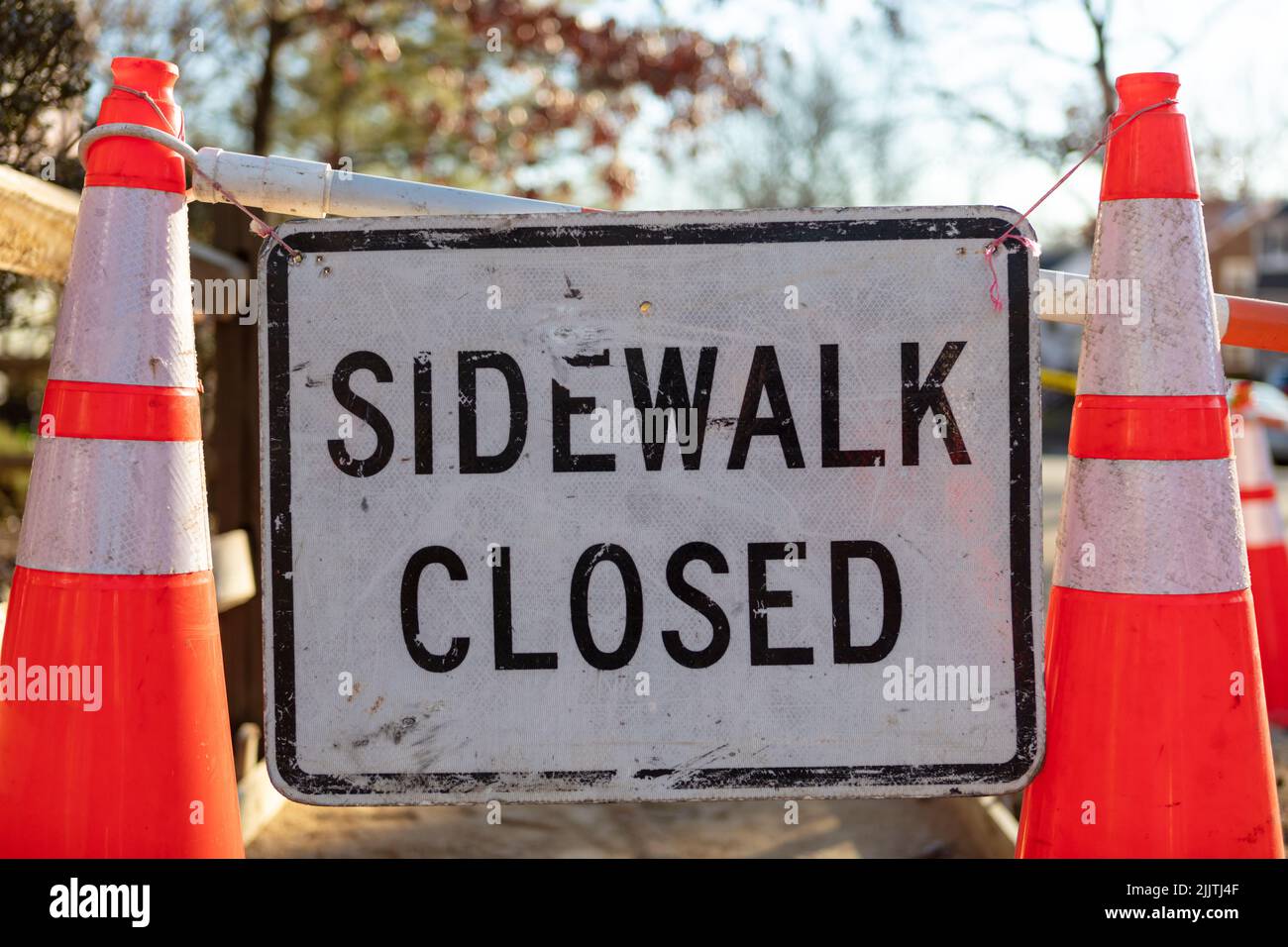 A sign with text 'Sidewalk closed' between two traffic cones in the street Stock Photo