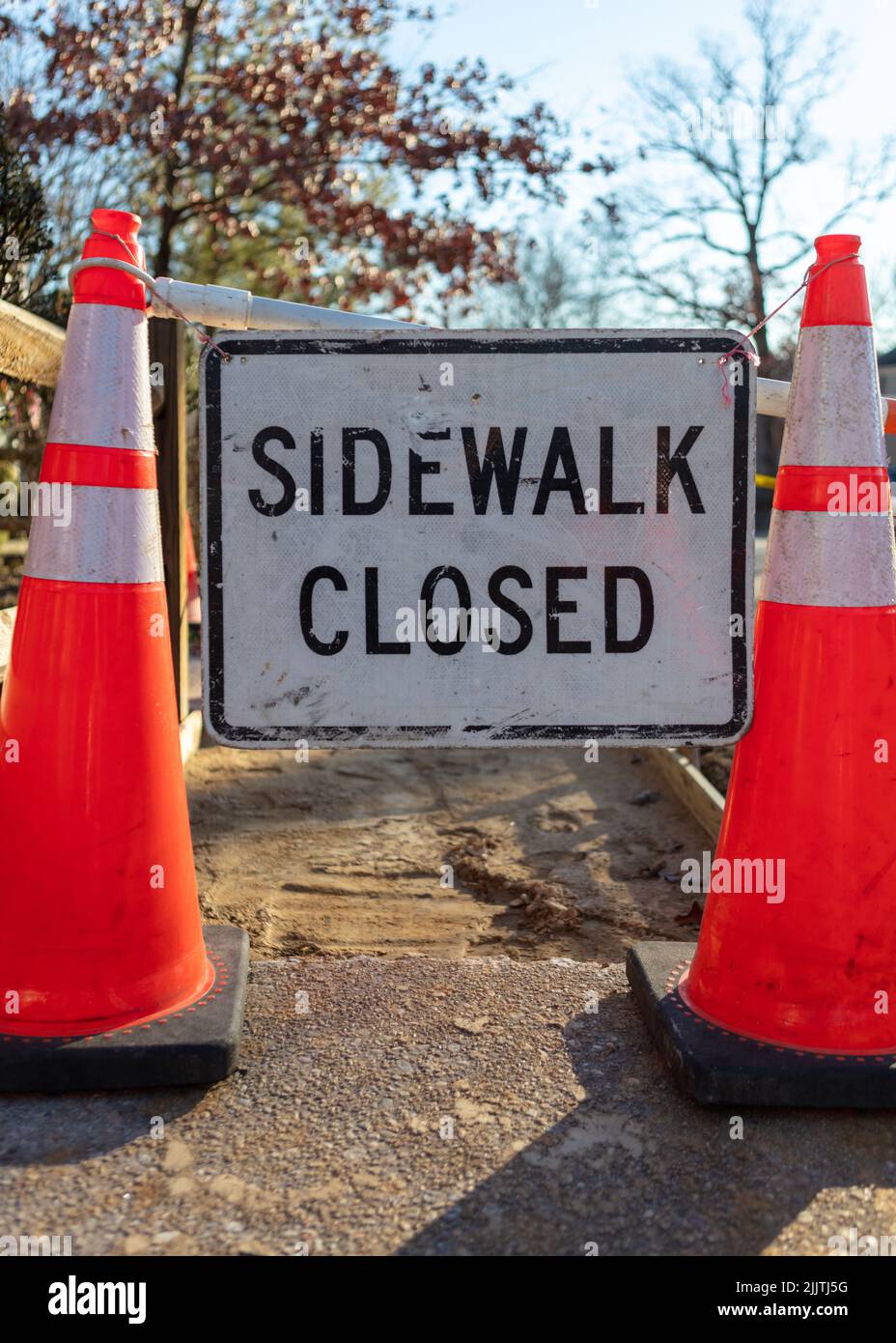 A sign with text 'Sidewalk closed' between two traffic cones in the street Stock Photo