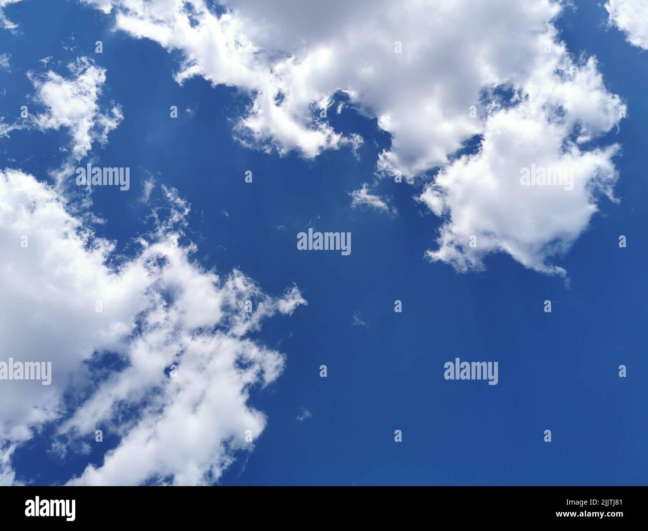 Cotton-like cumulative clouds in the blue clear sky Stock Photo