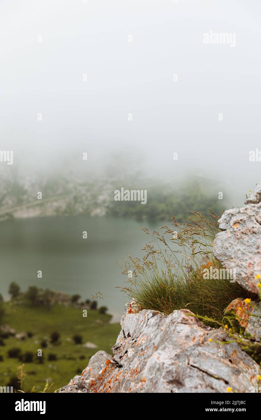 A selective focus of rocks in a foggy mountains with a lake on the background Stock Photo