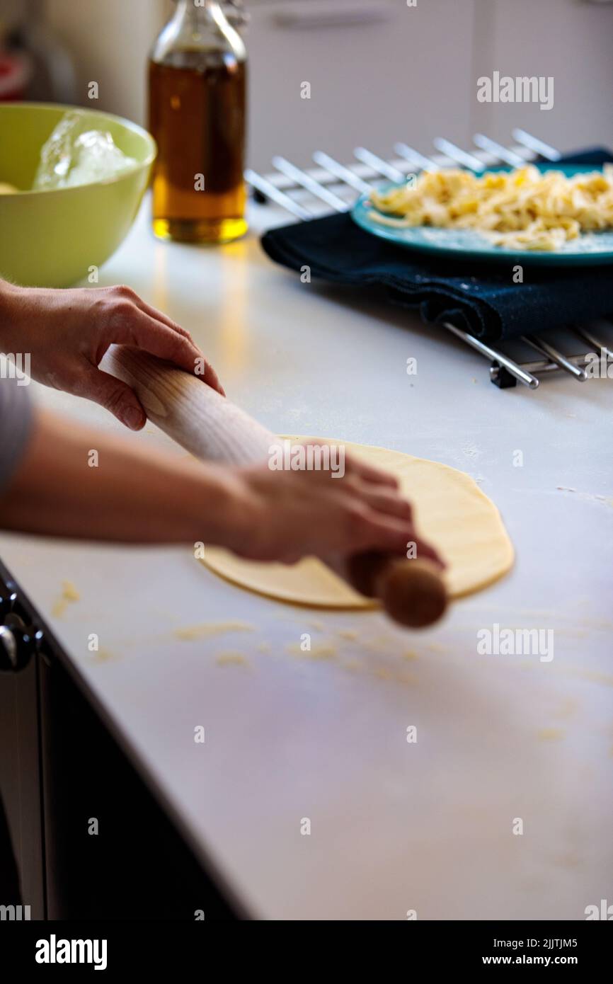 A vertical shot of a person using a rolling pin for dough Stock Photo