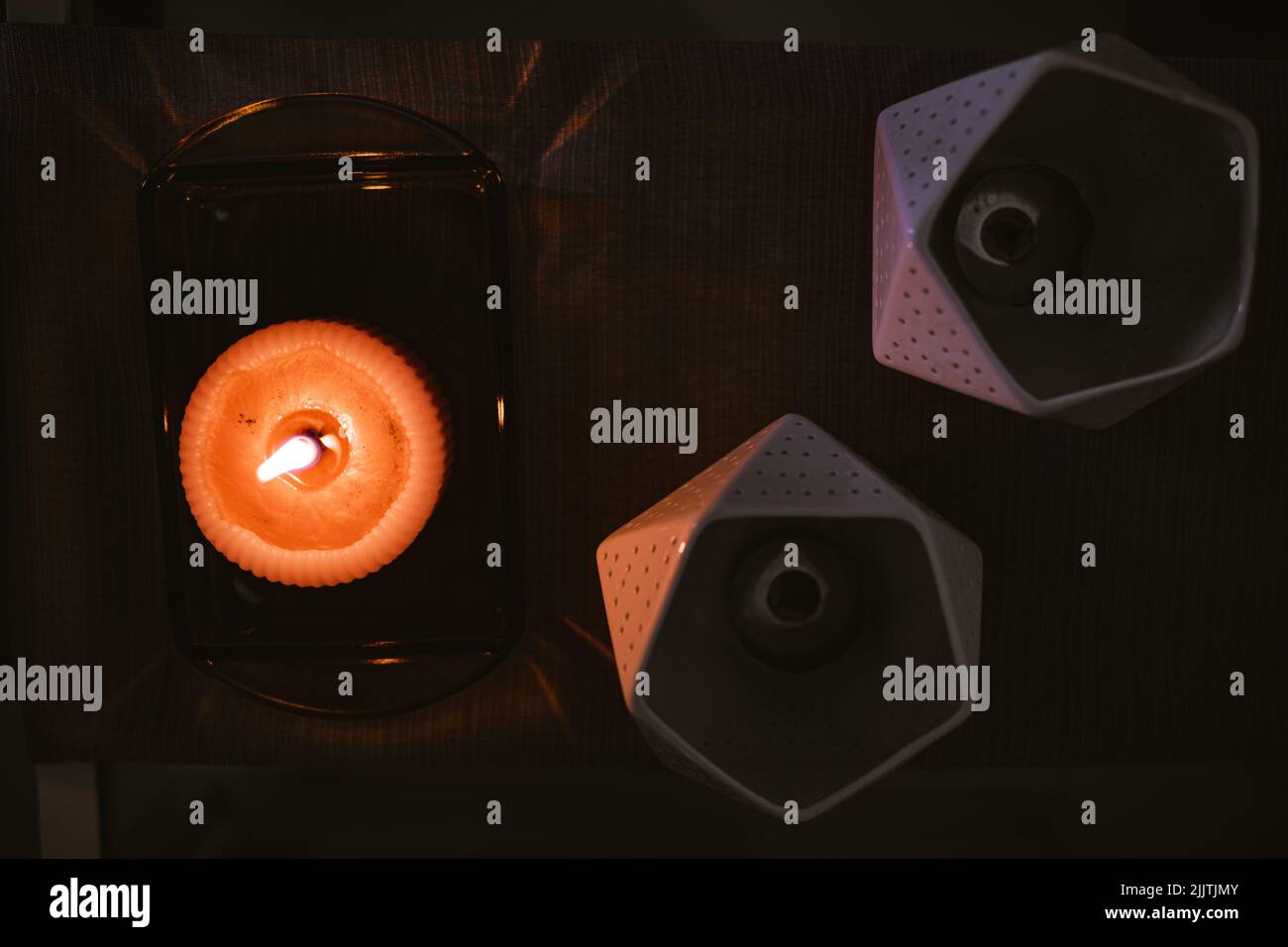 A top view of burning candle on a decorative tray and candle holders