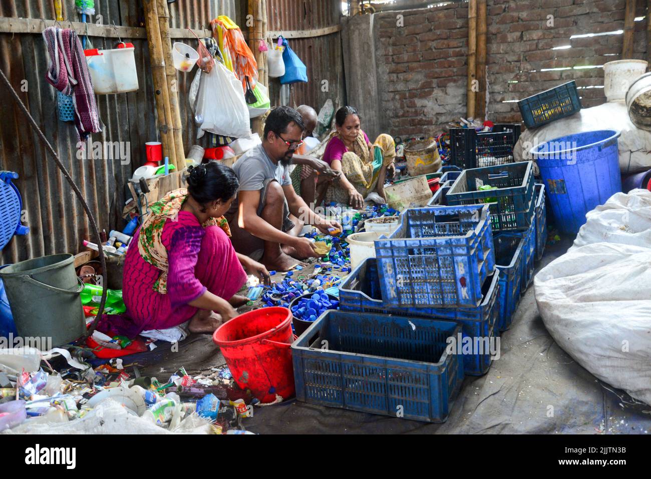 Laborers sort through polyethylene terephthalate (PET) bottles in a
