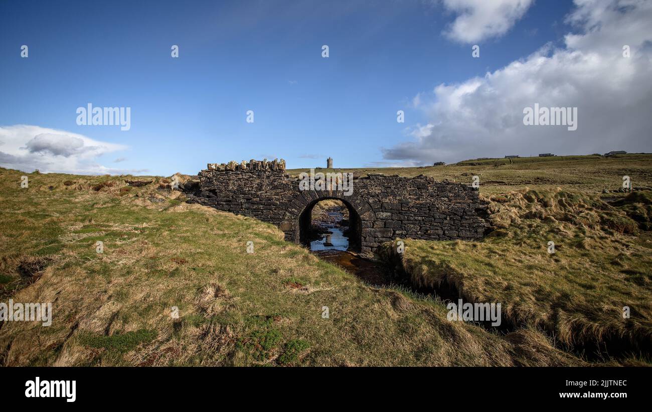 An arch stone bridge in a green meadow in the morning Stock Photo