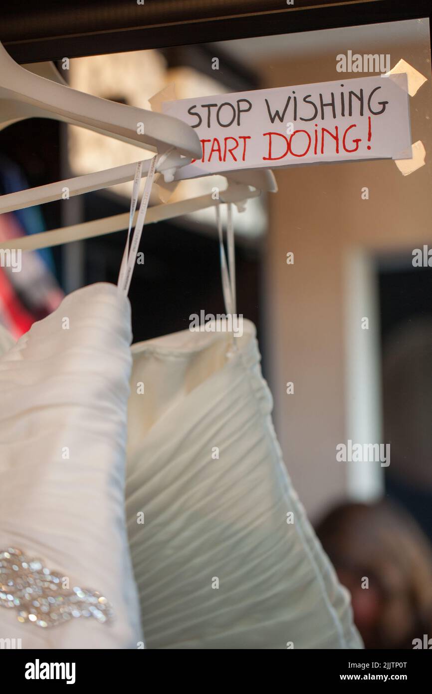 Love quote on a mirror next to the wedding dress at wedding, the quote says stop wishing, start doing. High quality photo Stock Photo