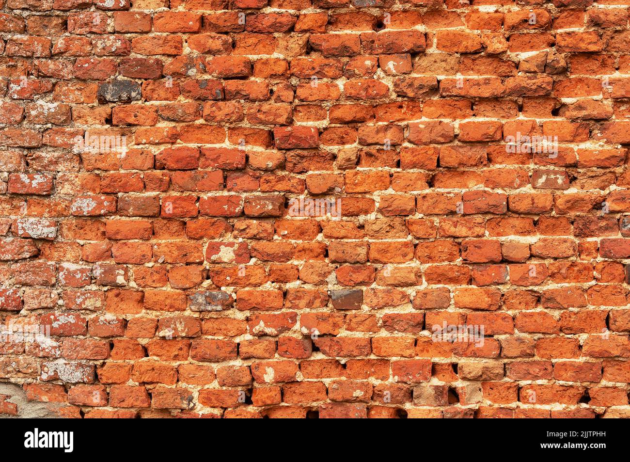Old red uneven brick wall. Vintage background. Abstract texture. Stock Photo