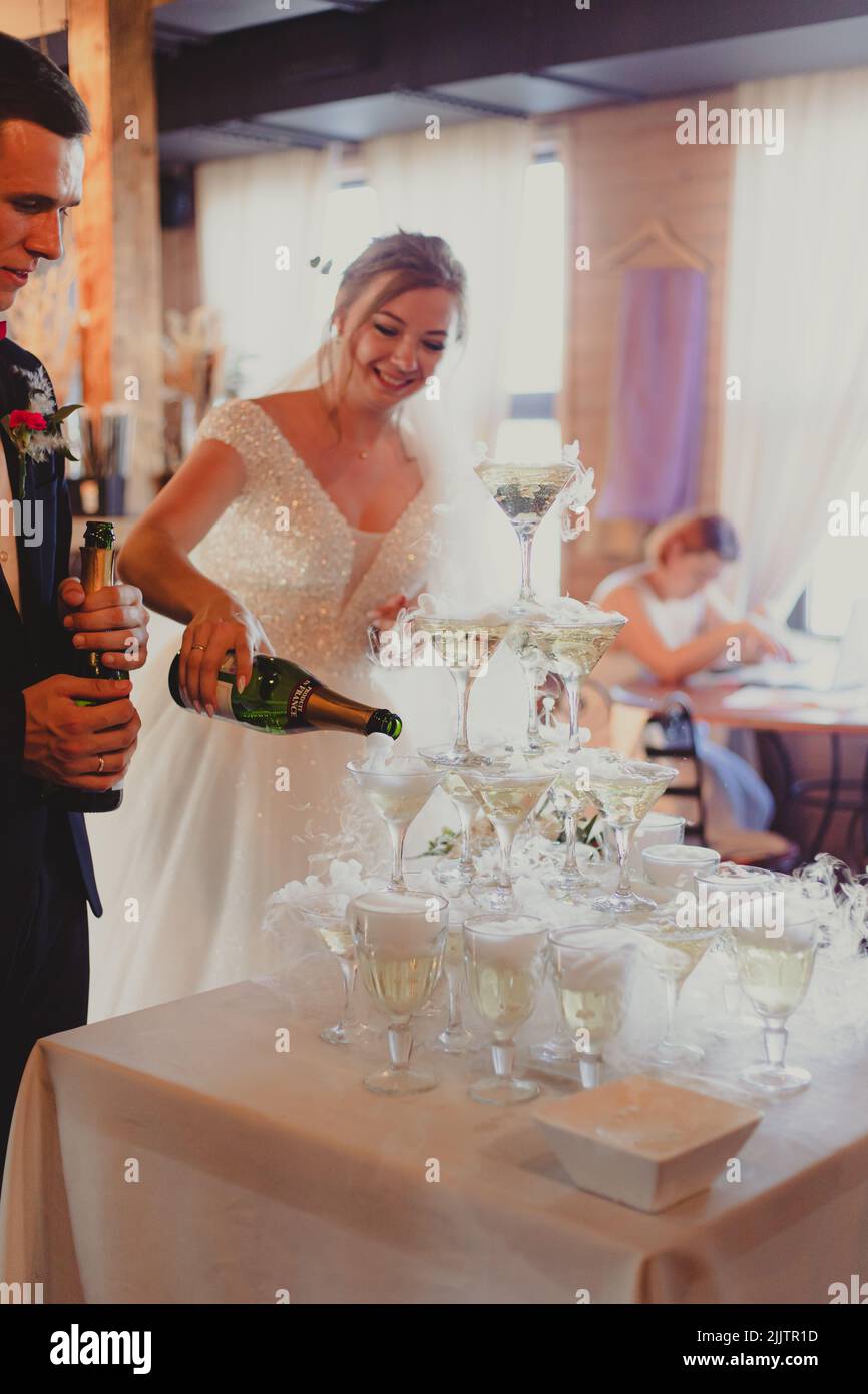The bride and groom fill the champagne fountain. Wedding article. A