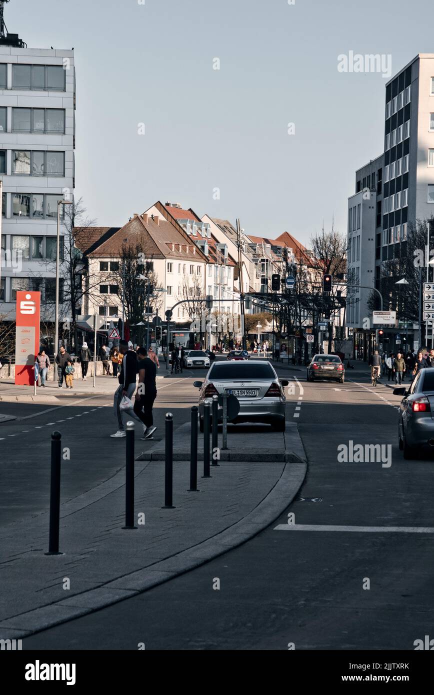 A vertical shot of an urban area with modern buildings and people on streets in Ulm City, Munster, Germany Stock Photo
