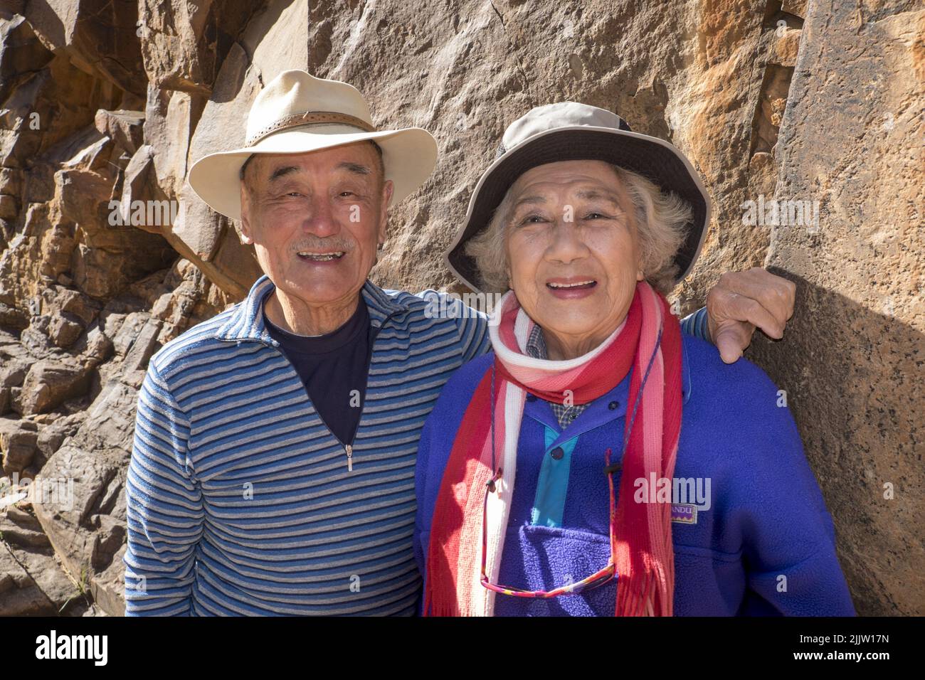 Australian born Chinese, self-funded, traveling retirees, Maurice Lee (86) and his wife, Wilma Lee (83), touring the Sacred Canyon in the Flinders Ranges, in South Australia. Both Maurice and Wilma active seniors, only gave up skiing a few years ago. Now they are travelling to fill their bucket list of places they've always wished to visit in Australia. They are about to celebrate their 62nd wedding anniversary.  Photo shows Maurice and Wilma, with one of the Aboriginal petraglyphs in the Sacred Canyon whish is near Wilpena Pound. Stock Photo