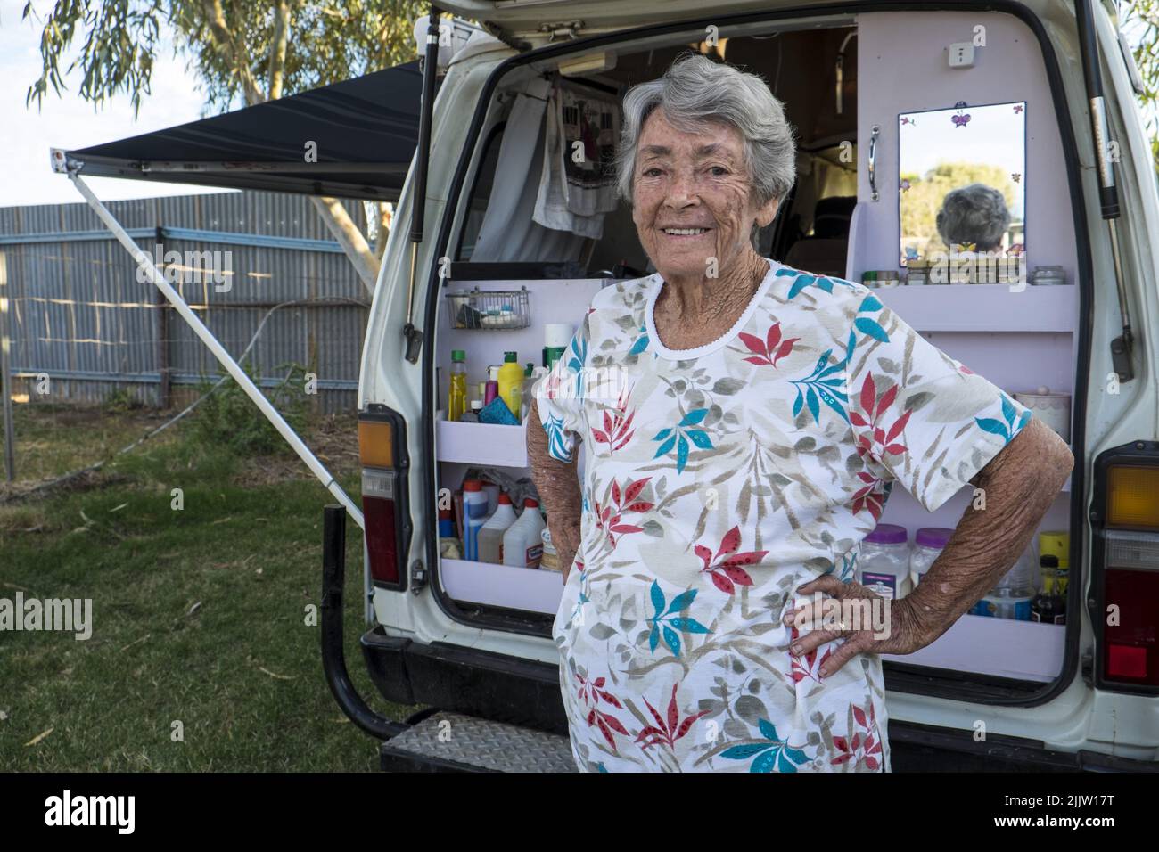 84 year old, traveler, pensioner, Thelma Evans with her Toyota Hi-Ace van in the tourist park in Winton, Queensland.   In 1988 while traveling around Ausralia in a caravan with her husband, Thelma became a widow. After a period of mourning she decided to keep traveling. She replaced the caravan with a more easily handled van and since that time she has driven over 400,000 km crisscrossing the country. She has travelled the Gibb River Road, five times and has an encyclopeadic knowledge of the roads, rivers, mountains, billabongs and campsites of Australia.  Her campervan, fitted out by her carp Stock Photo