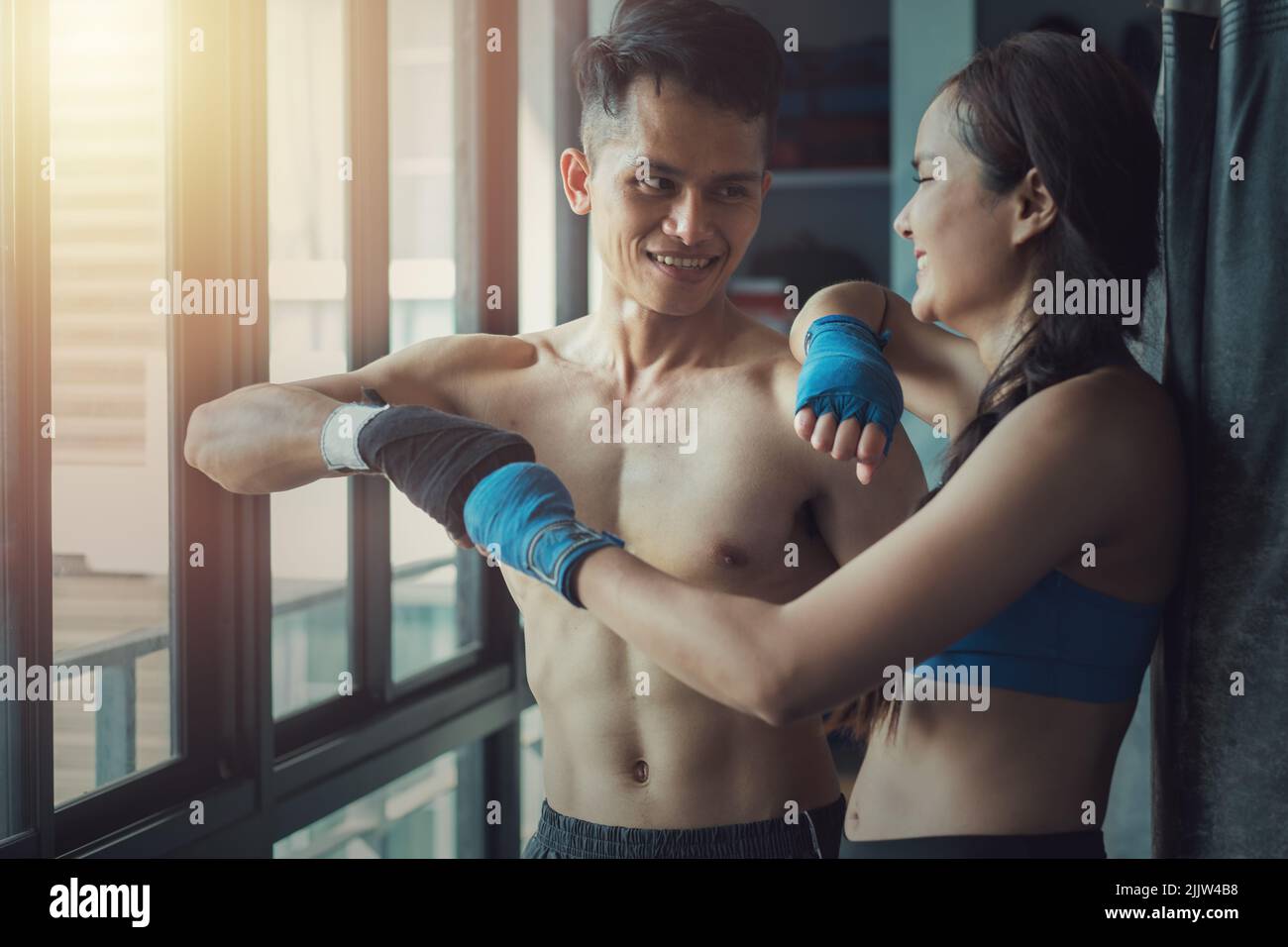 Two young fit professional Southeast Asian boxers smiling and bumping ...